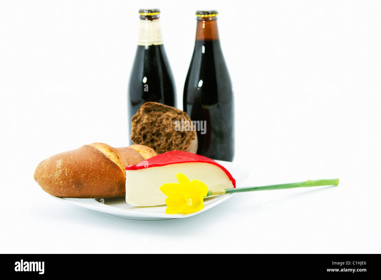 Deux bouteilles de bière brune sont placés avec des pains à grains entiers, du fromage à croûte rouge sur une plaque blanche dans un vrai pays, le déjeuner. Banque D'Images