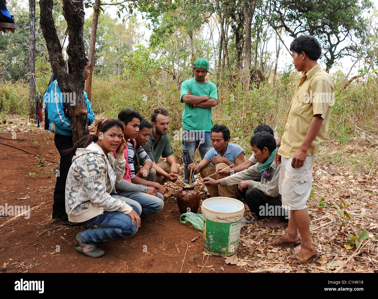 Bunongs Hommes buvant du vin de riz à une célébration de mariage la campagne. Le cochon est une offrande sacrificielle pour les invités à la fête sur Banque D'Images