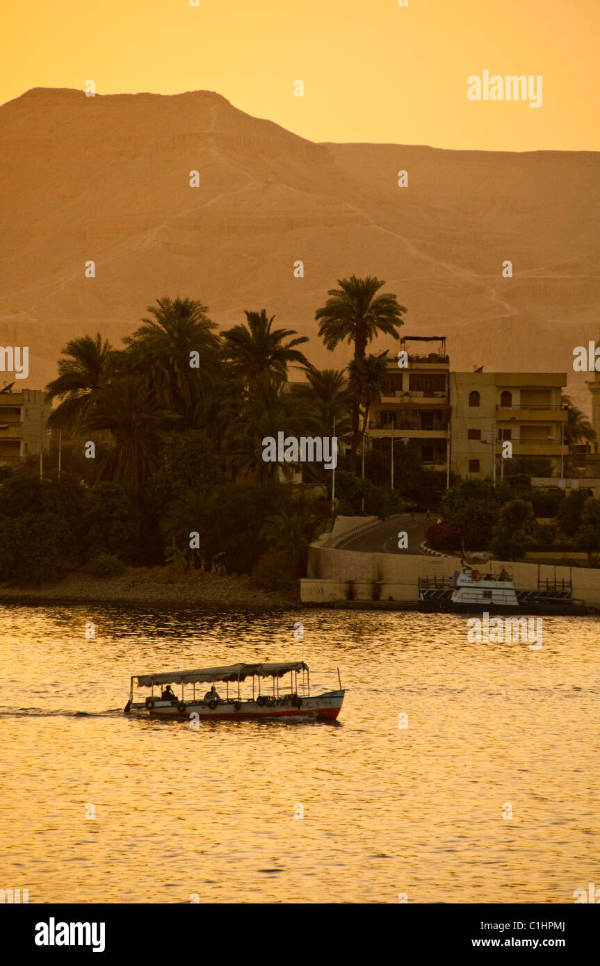 Une Felouque égyptienne traditionnelle bateau navigue sur le Nil à Louxor, Egypte avec un traversier passant. Banque D'Images