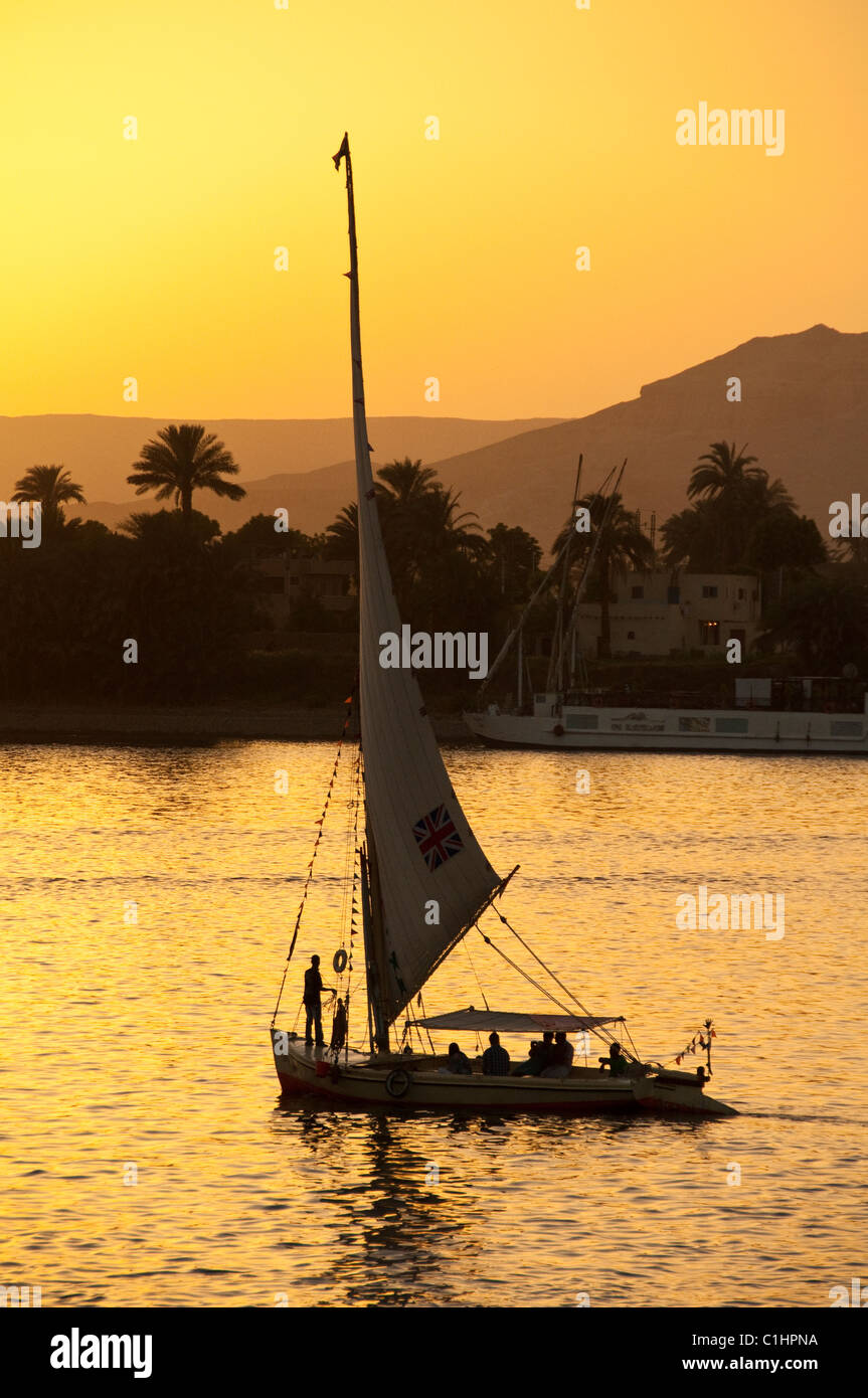 Une Felouque égyptienne traditionnelle bateau navigue sur le Nil à Louxor, Egypte avec un traversier passant. Banque D'Images