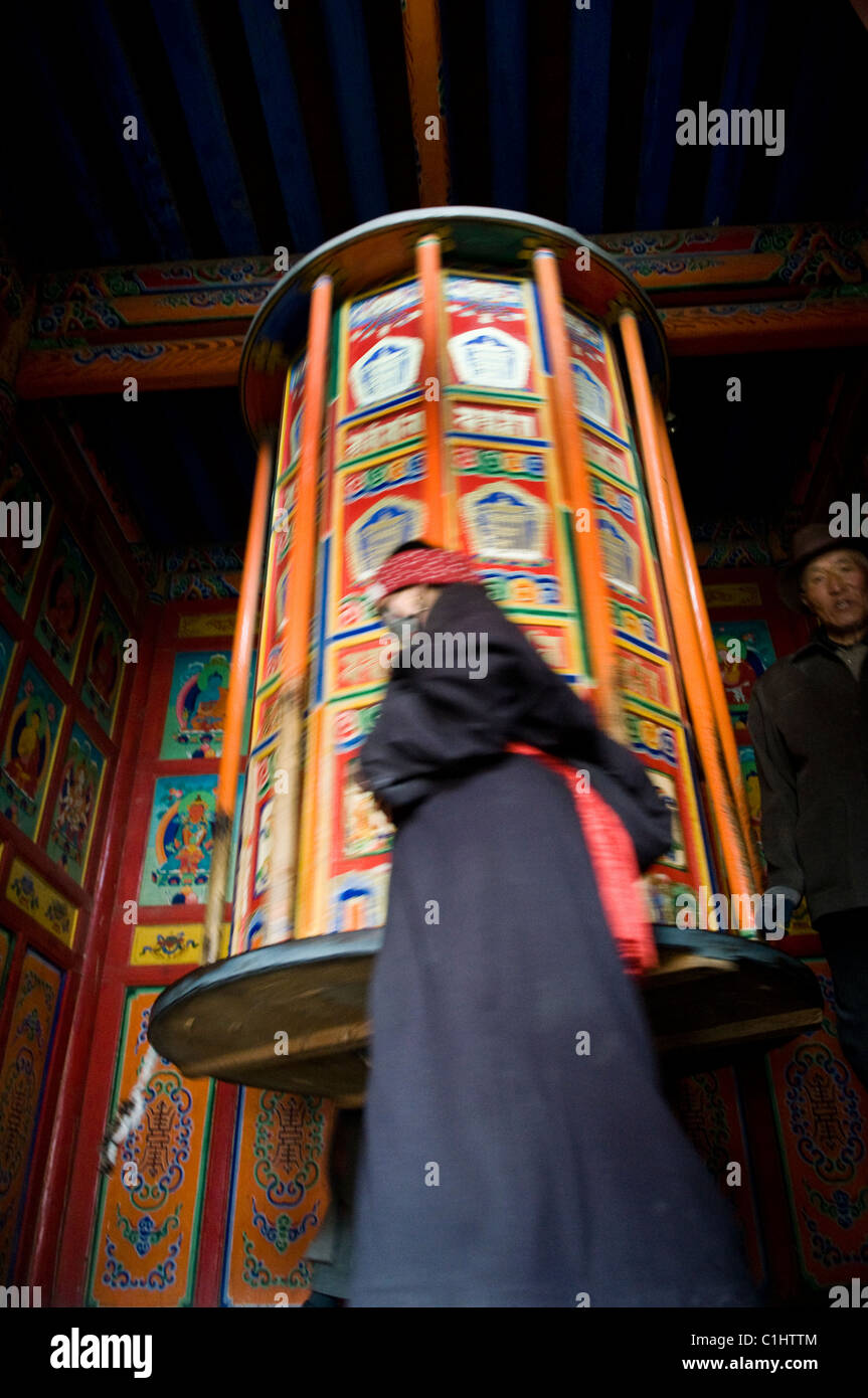 Un tibétain femme tournant un gros moulin à prière dans le monastère de Labrang à Xiahe. Banque D'Images