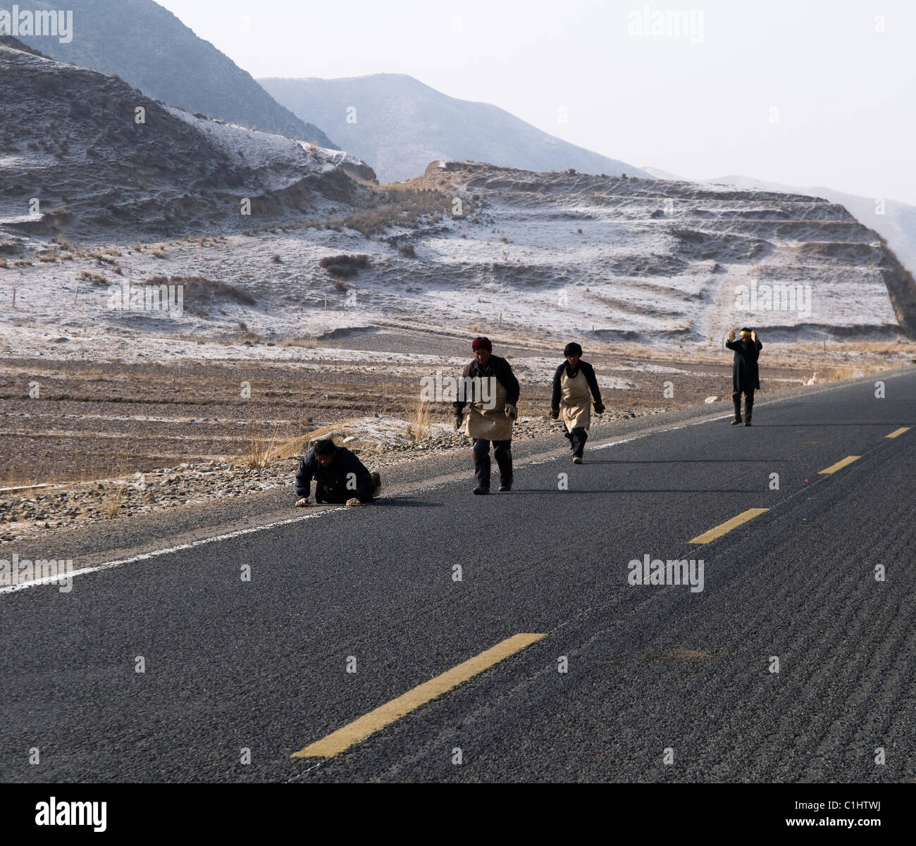 Pèlerins Tibétains faisant une marche en se prosternant sur leur façon de monastère de Labrang. Banque D'Images