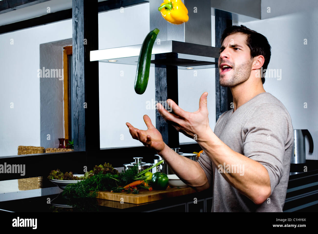 Jeune homme jonglant avec le concombre et le poivron jaune Banque D'Images