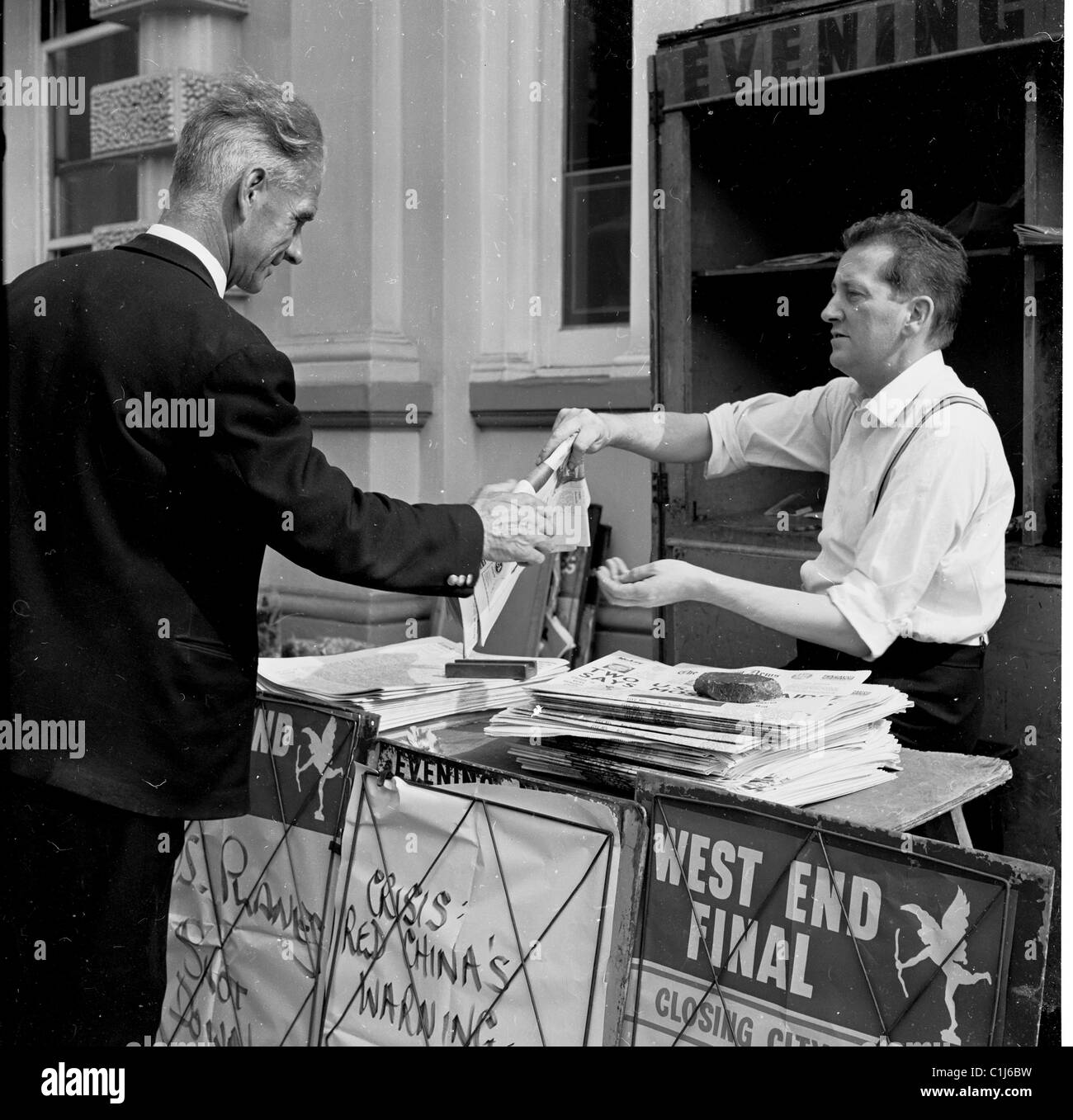 Années 1950, historique, un gentleman achetant le Evening News d'un vendeur de journaux dans un kiosque de trottoir, Londres, Angleterre, Royaume-Uni. Banque D'Images