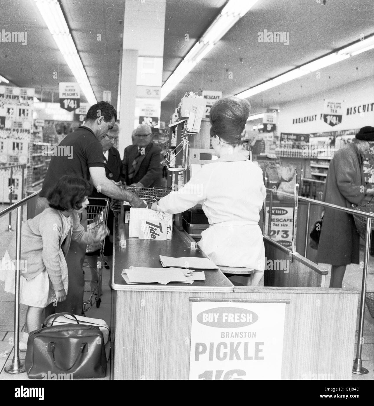 1960s, à l'intérieur d'un nouveau supermarché à la caisse ou à la caisse, une jeune fille avec leurs propres sacs de retenue aidant son père avec le shopping, Angleterre, Royaume-Uni. Banque D'Images