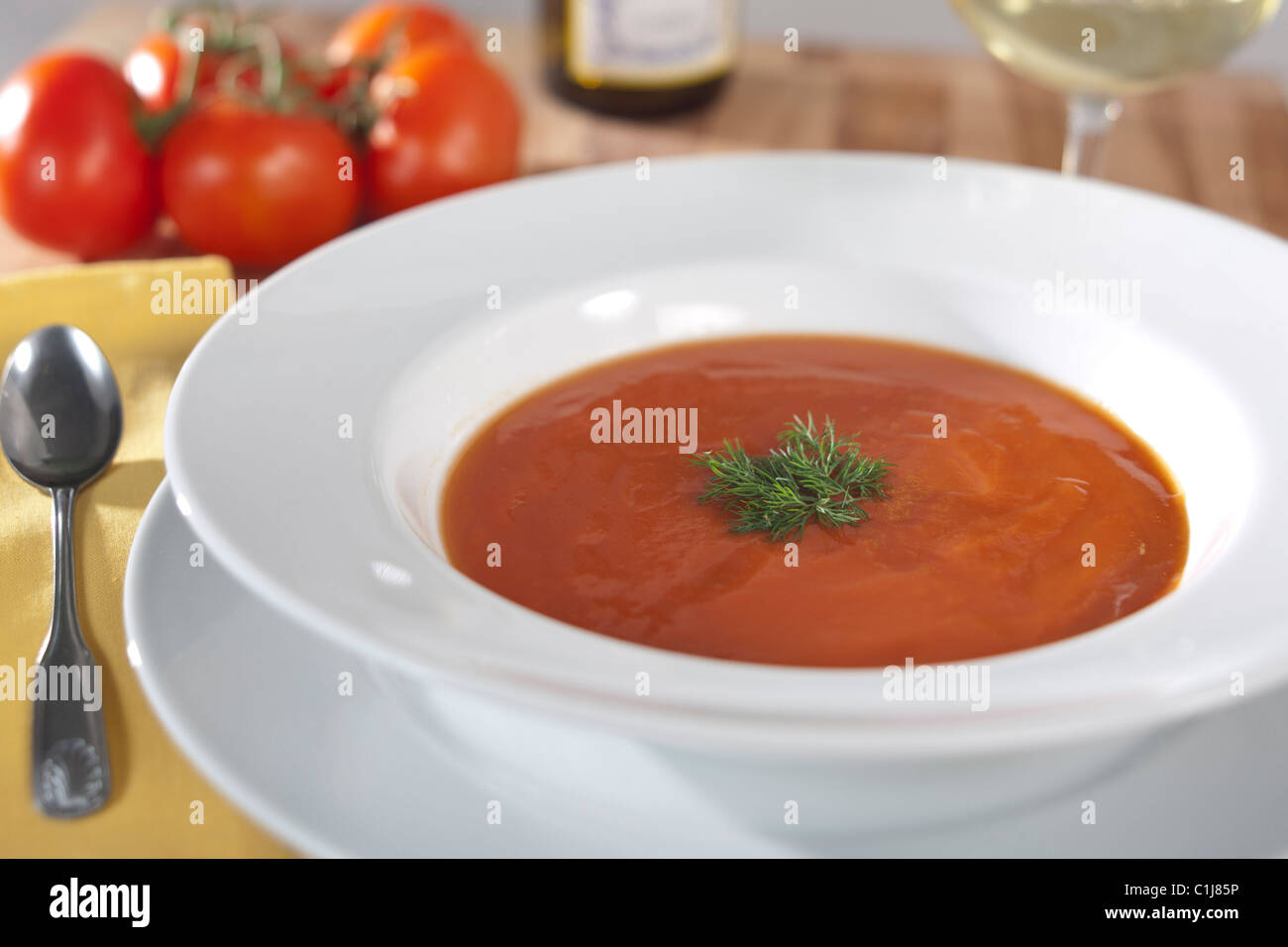 Bol de soupe de tomate à l'aneth, tomates fraîches et un verre de vin blanc. Banque D'Images