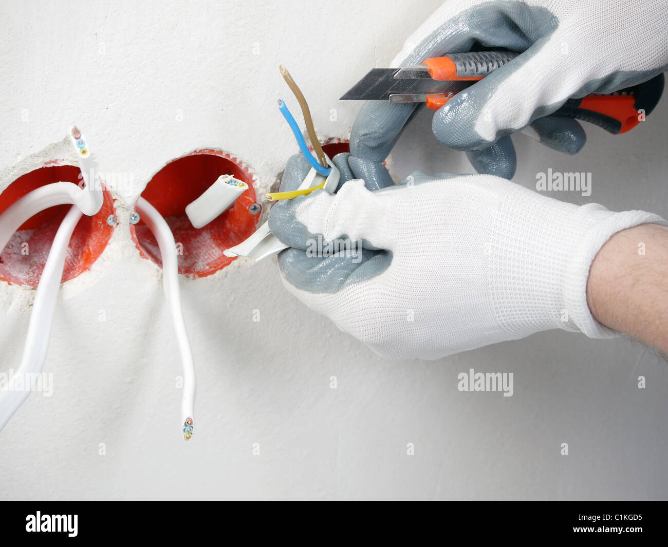 Les mains de l'électricien de fils électriques de dénudage pour prise murale Banque D'Images