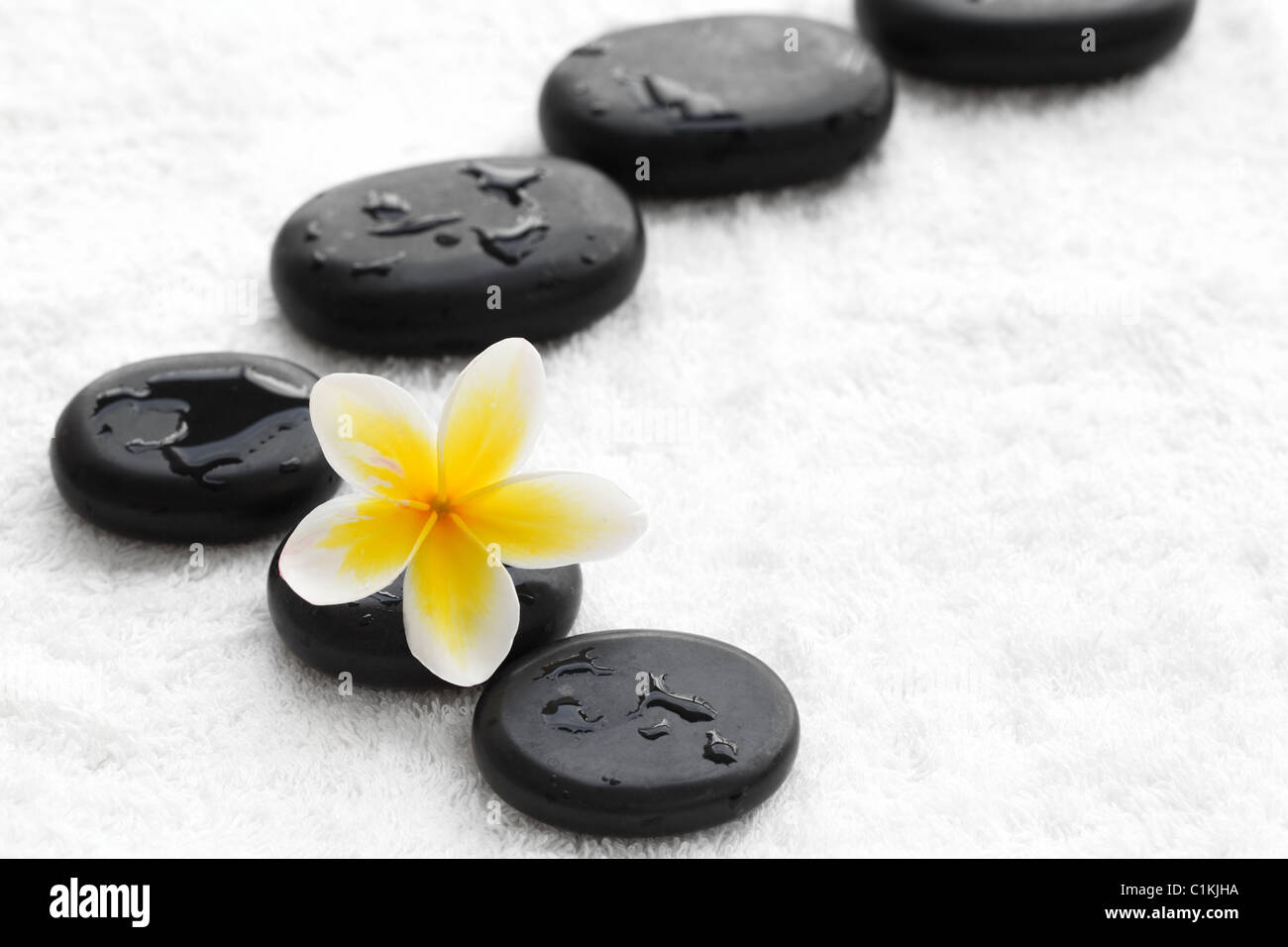 Pierres zen avec fleur de frangipanier sur serviette blanche Banque D'Images