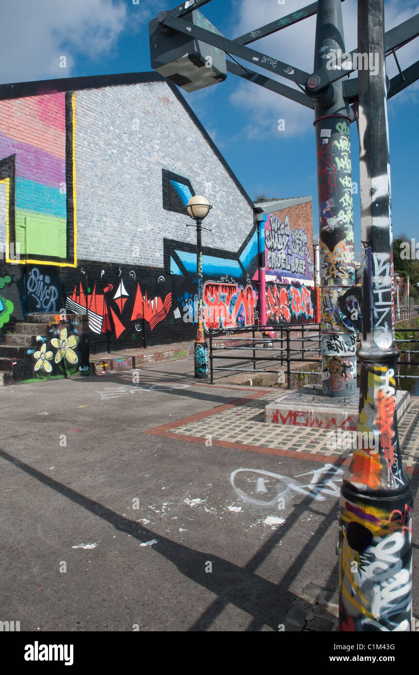 Des murs couverts de graffitis et du mobilier urbain sur les rives de la rivière Irwell, Salford. Banque D'Images