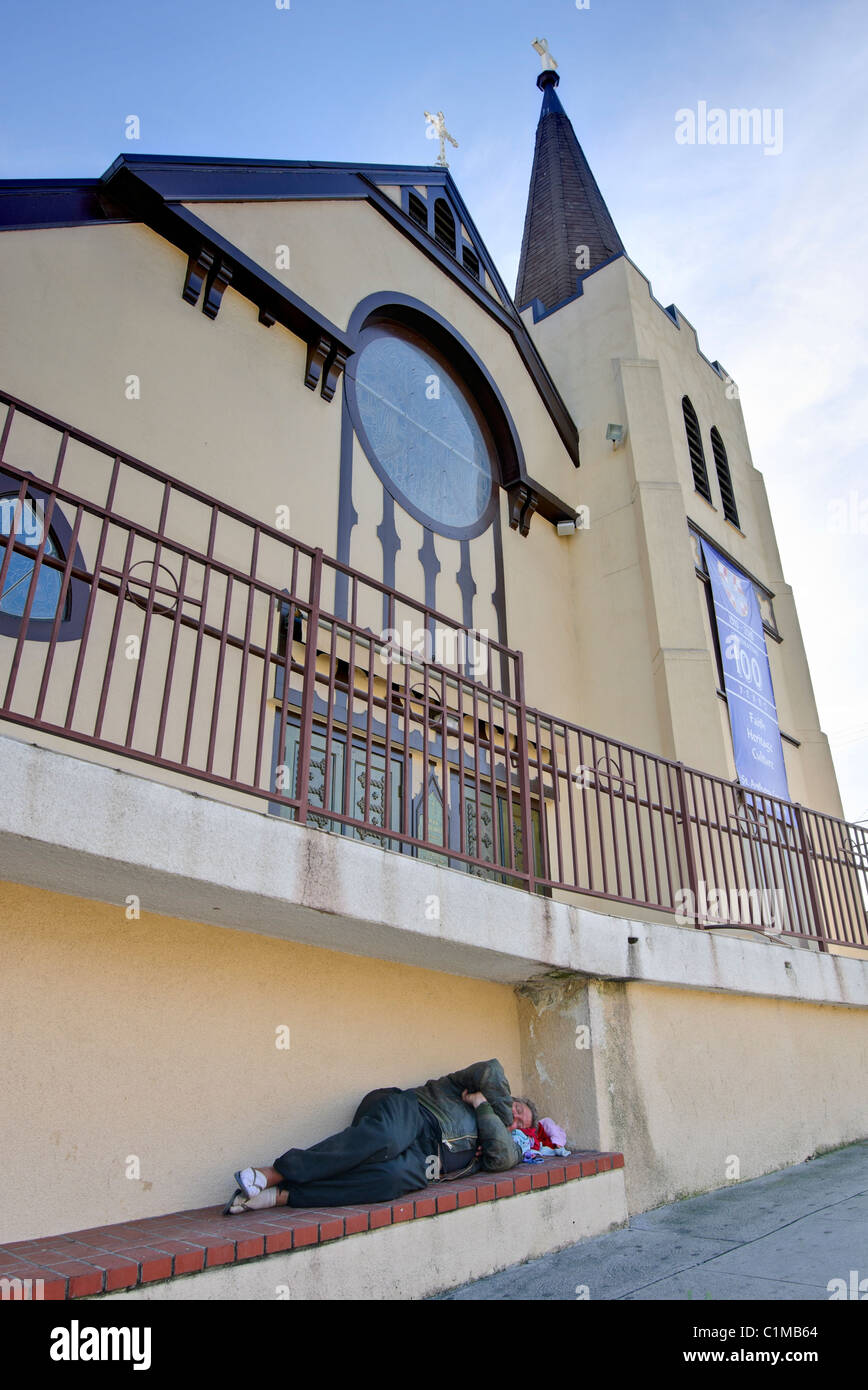 Un sans-abri dormir par une église locale. Banque D'Images