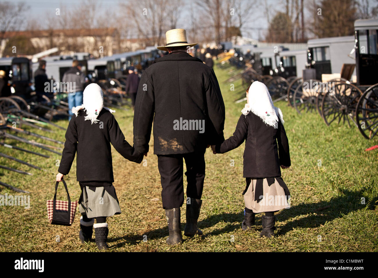 Homme Amish détient les mains avec ses filles à la vente aux enchères annuelle de boue et Vertou, PA. Banque D'Images