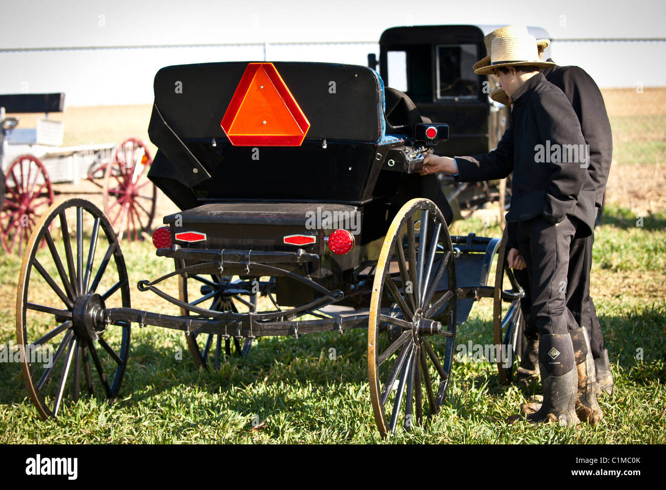 Les jeunes hommes inspecter un cheval Amish buggy au cours de l'assemblée annuelle pour soutenir la vente de boue les pompiers en Vertou, PA. Banque D'Images