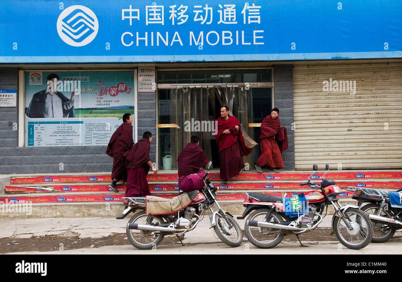 Moines bouddhistes tibétains en laissant un China mobile shop. Banque D'Images