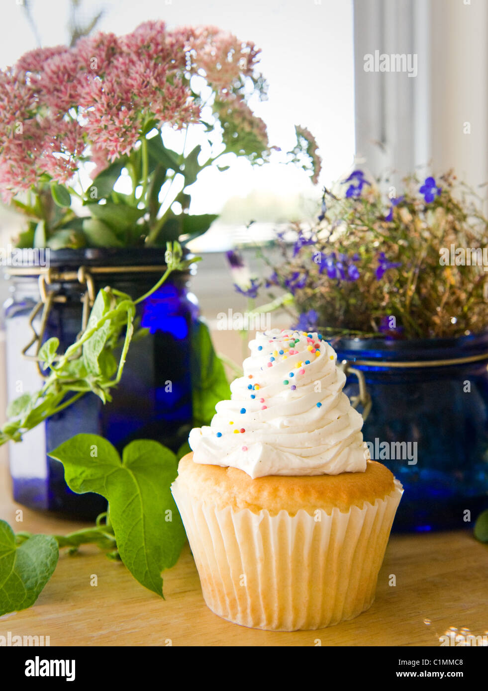 Un petit gâteau entouré de fleurs frais de la campagne Banque D'Images
