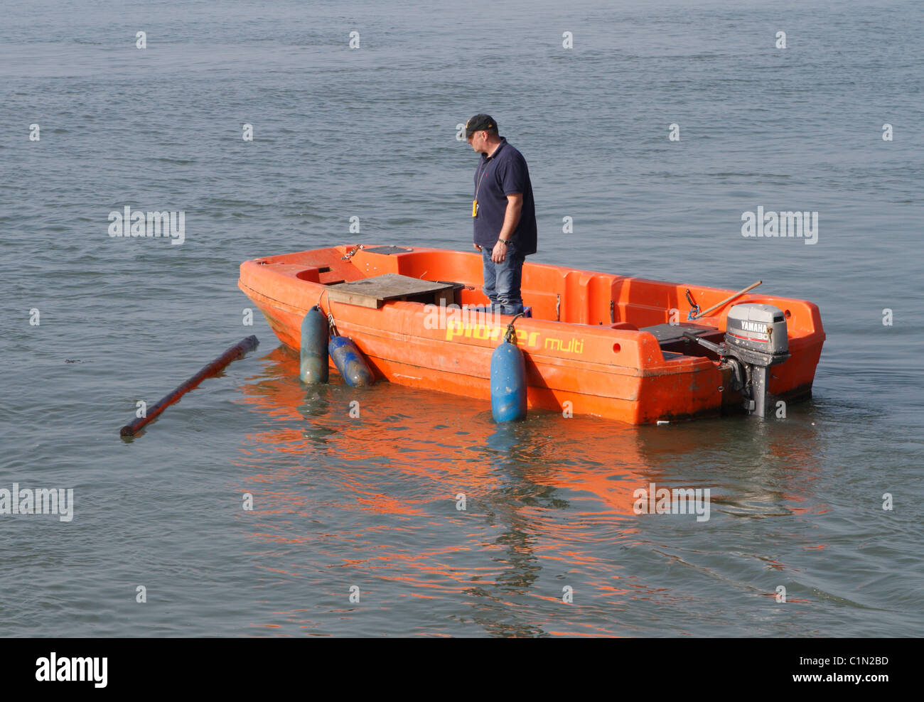 La collecte de bois flottant au large d'un port qui représente un danger pour les petits bateaux Banque D'Images