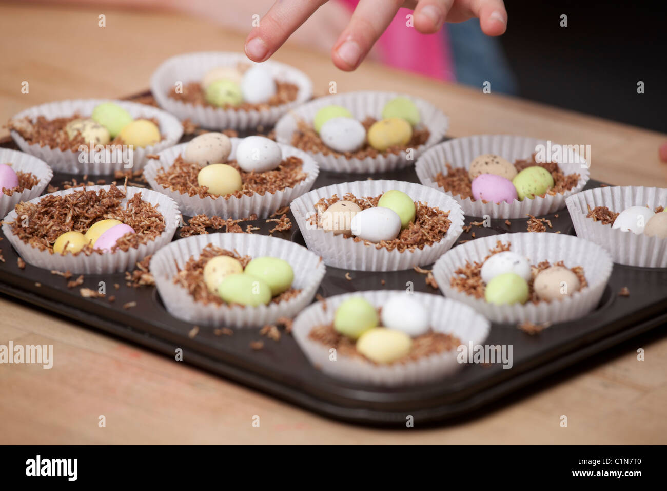 Les enfants faire de nid de Pâques cupcakes avec shredded wheat et mini des œufs en chocolat / Chocolat Mini-oeufs. Banque D'Images