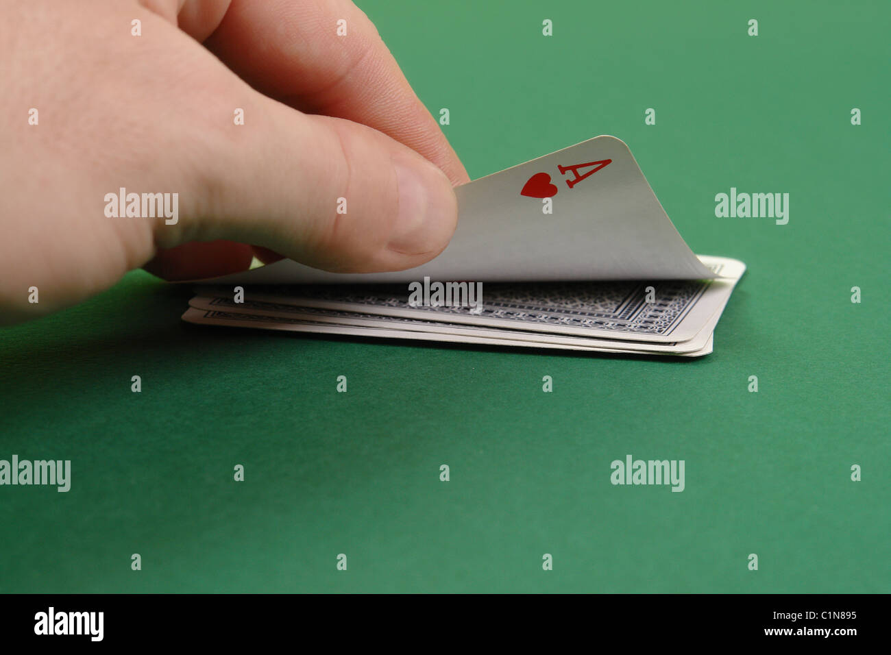 La main de joueur révélant Ace of Hearts sur table verte Banque D'Images