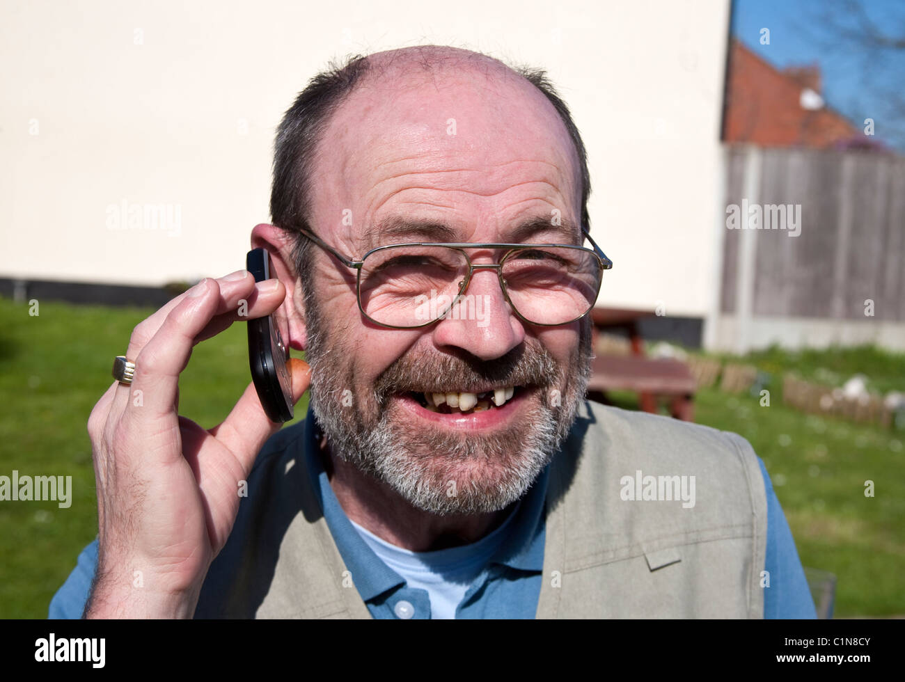 Homme de 60 ans avec l'aide de téléphone mobile en riant barbe Banque D'Images