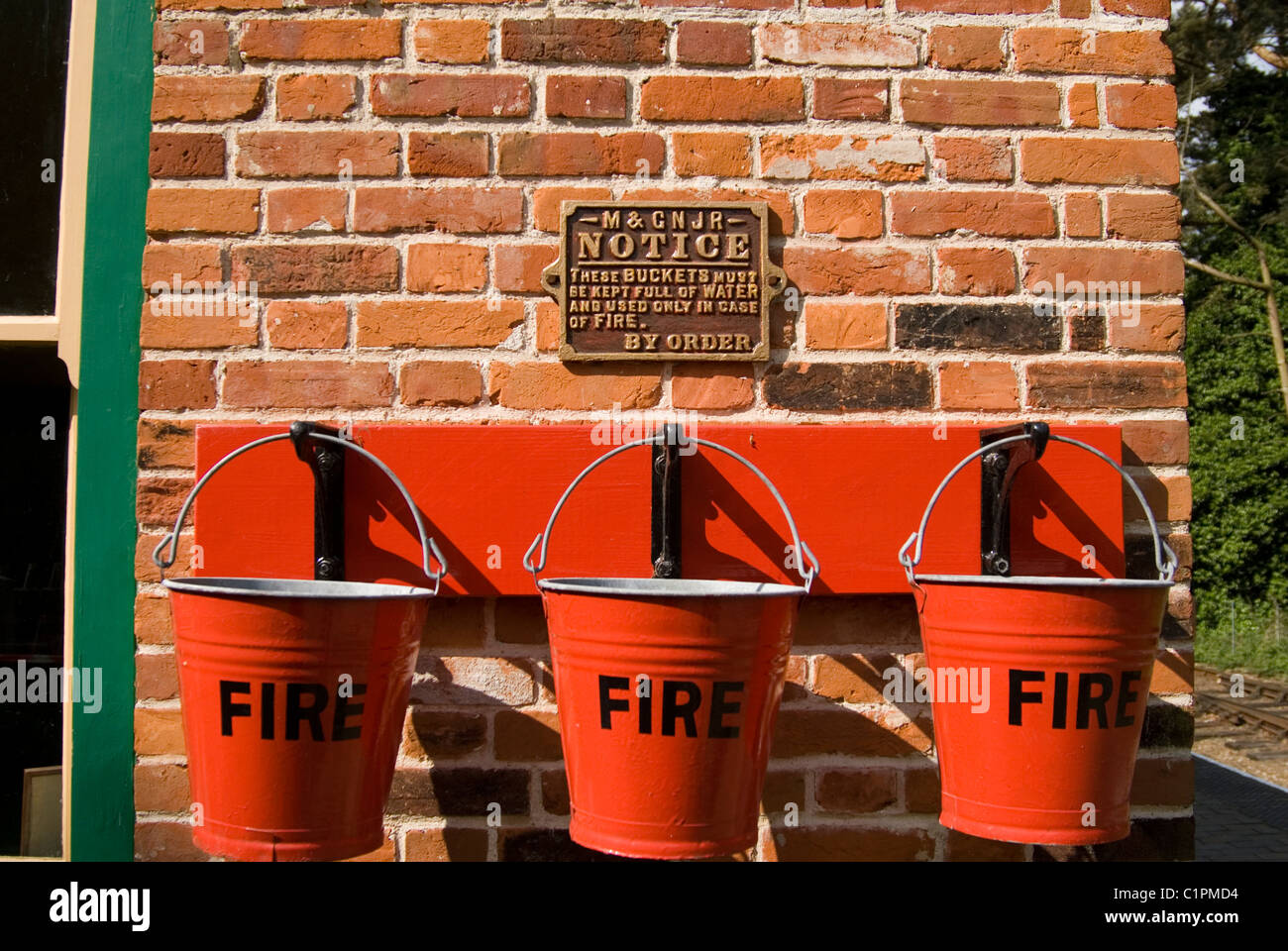 L'Angleterre, Norfolk, Weybourne, trois seaux d'incendie rouge sur le mur Banque D'Images