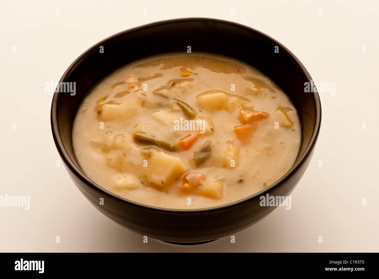 Soupe de légumes dans un bol en céramique noire sur fond blanc. Banque D'Images