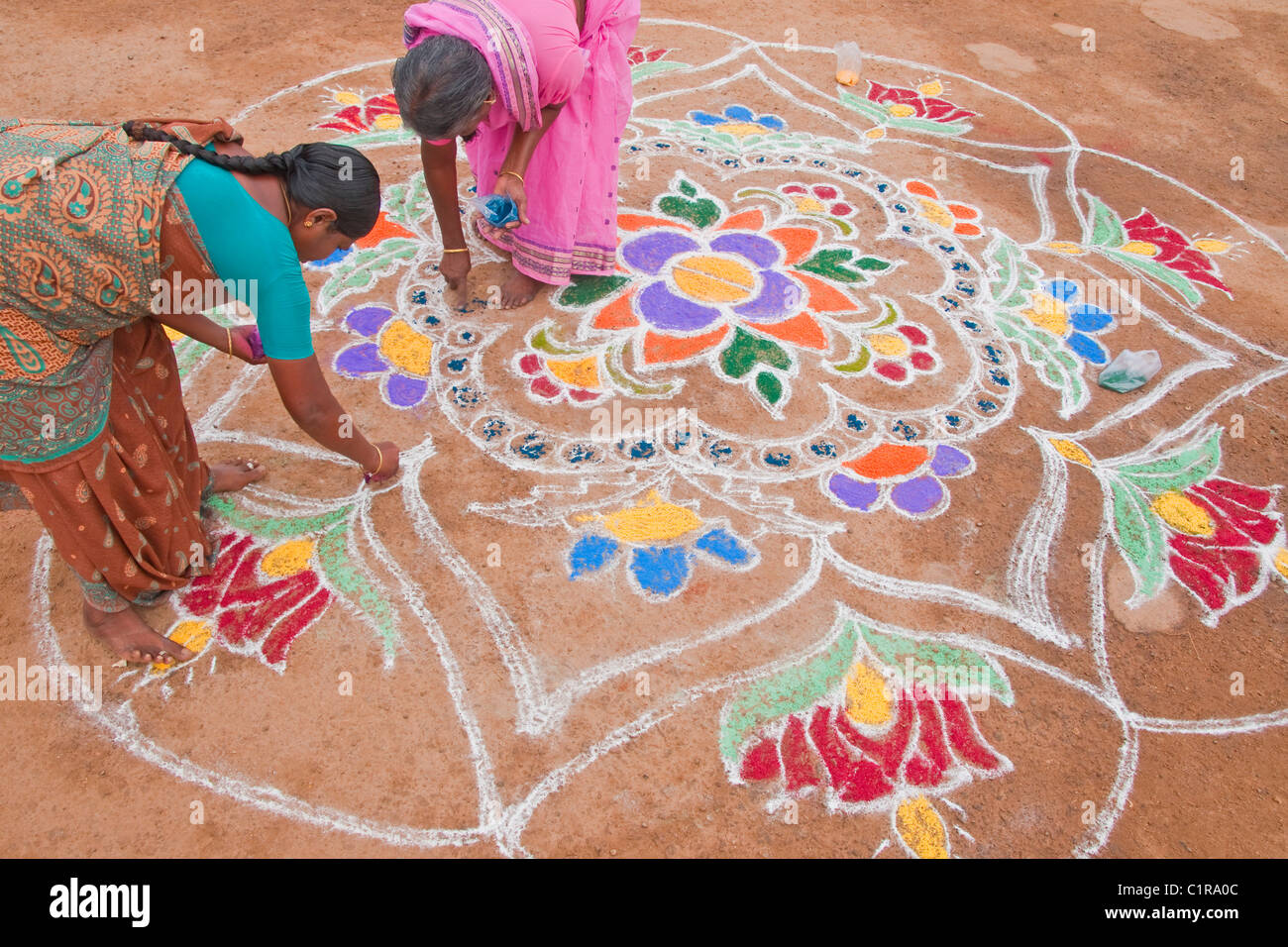 Les femmes du quartier de décoration avec de la craie en vue de la conception de Pongal Festival Banque D'Images