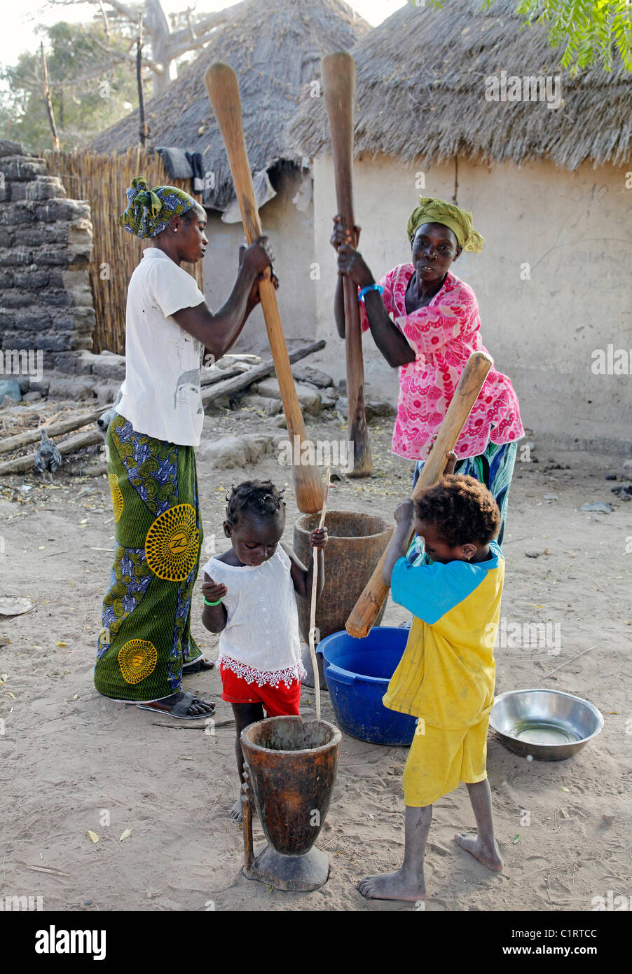 Femme et enfant battre le mil, maïs, sorgoum à l'aide de mortier et pestel. Sénégal Banque D'Images