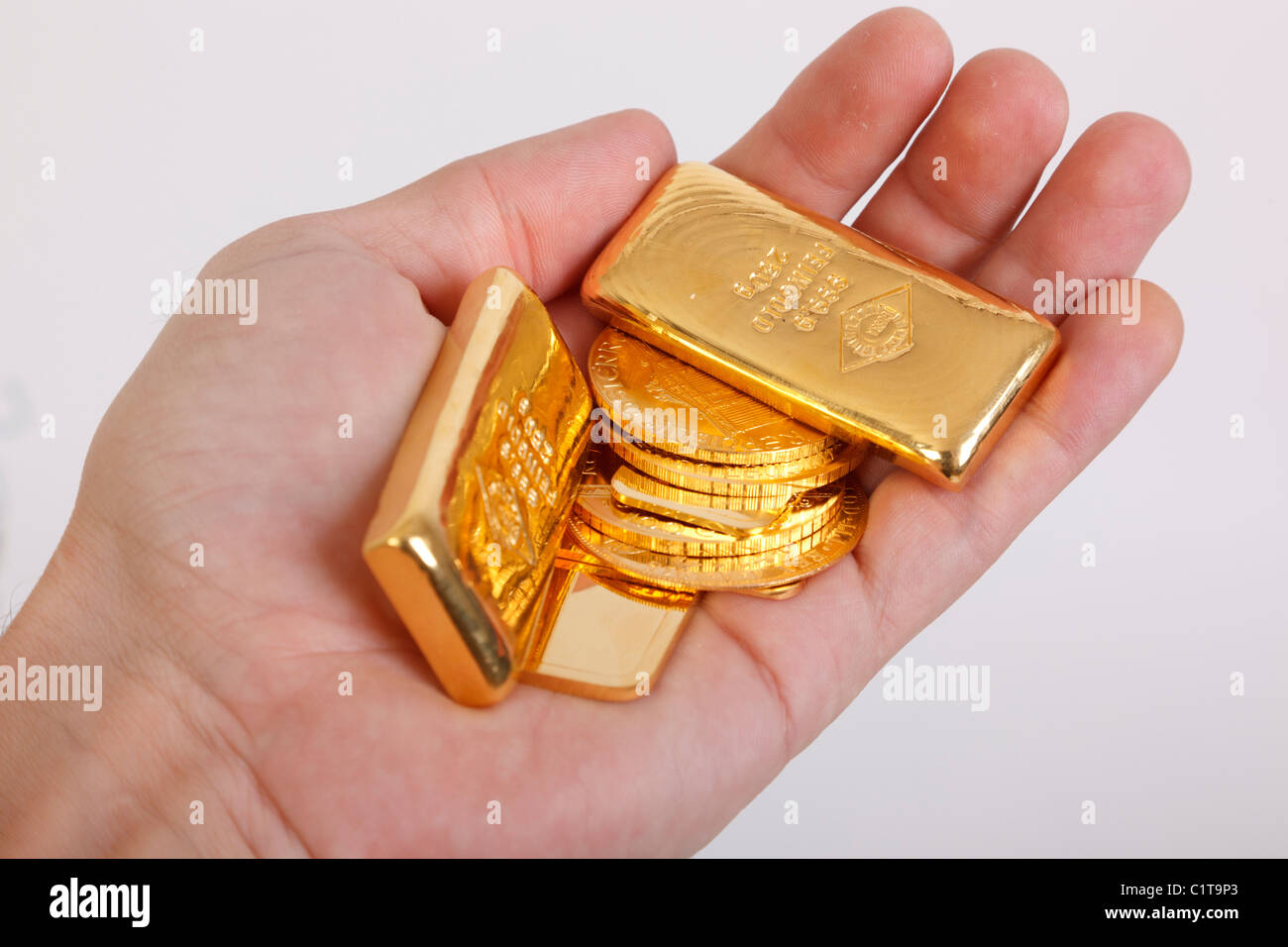 Barres d'or et de pièces d'or dans la main Banque D'Images