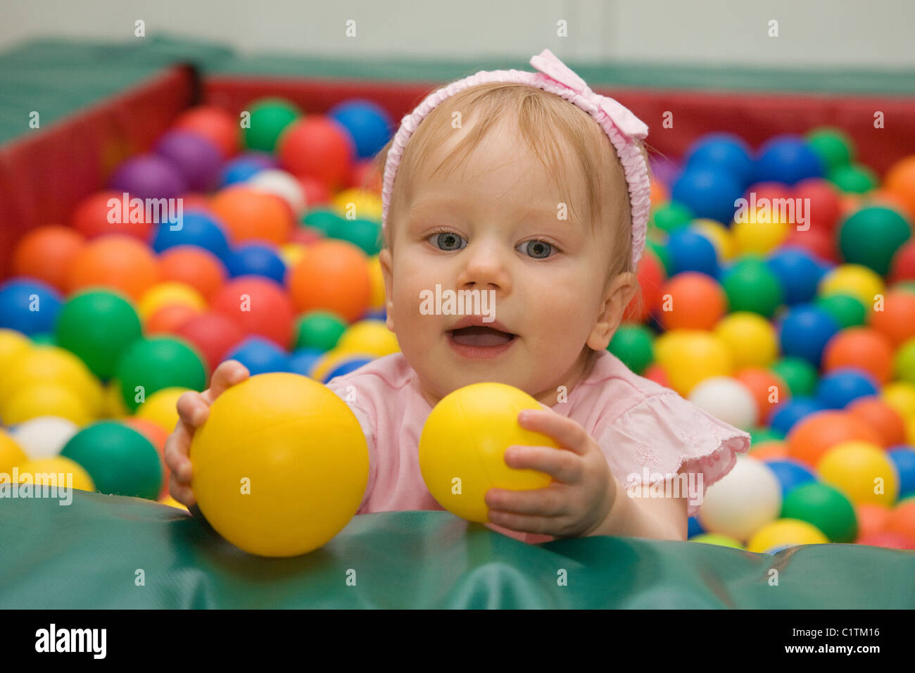 Un an Caucasian Baby Girl en aire de jeux avec des boules de jouet Banque D'Images