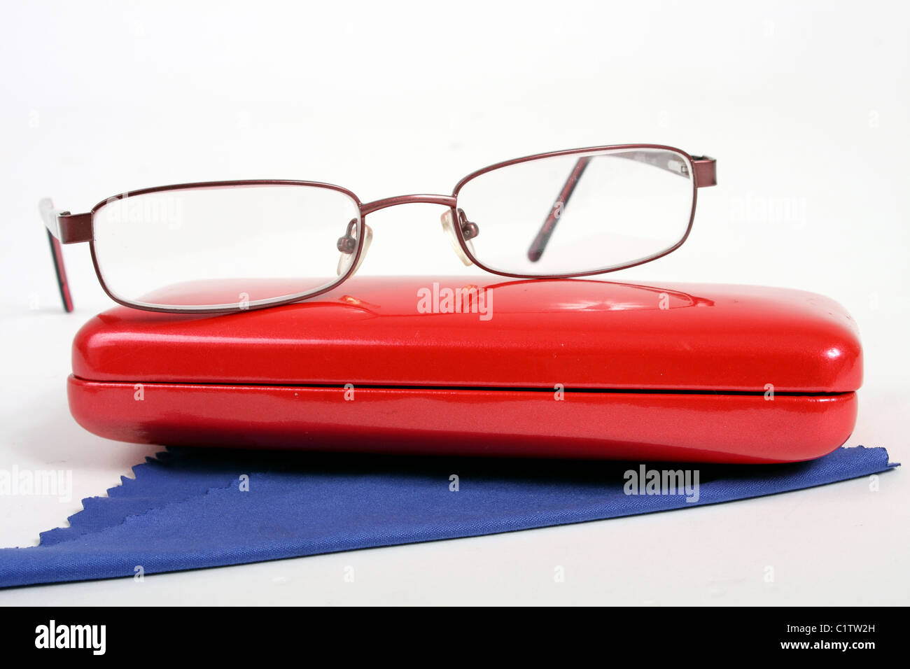 Une paire de lunettes de lecture sur un Bourgogne blanc coupé par un arrière-plan bleu rouge à lunettes et chiffon de nettoyage. Banque D'Images