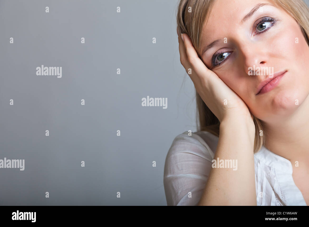 Triste, déprimé young blonde woman sur fond gris neutre Banque D'Images