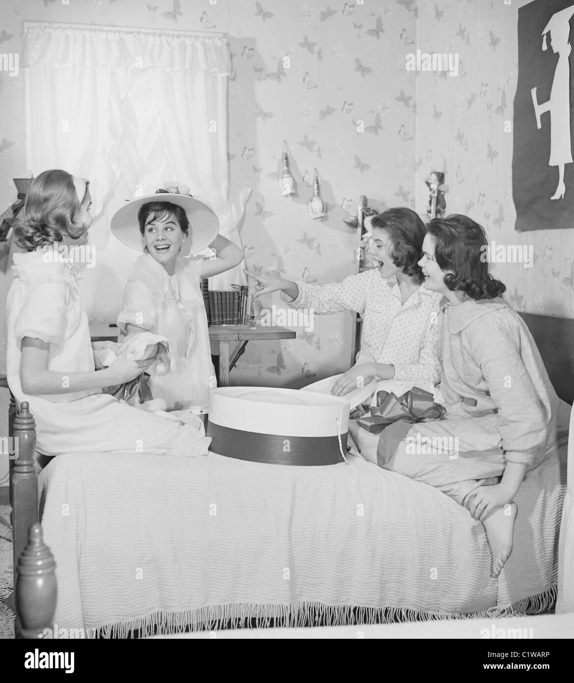 Quatre jeunes femmes chapeaux montage dans la chambre Banque D'Images