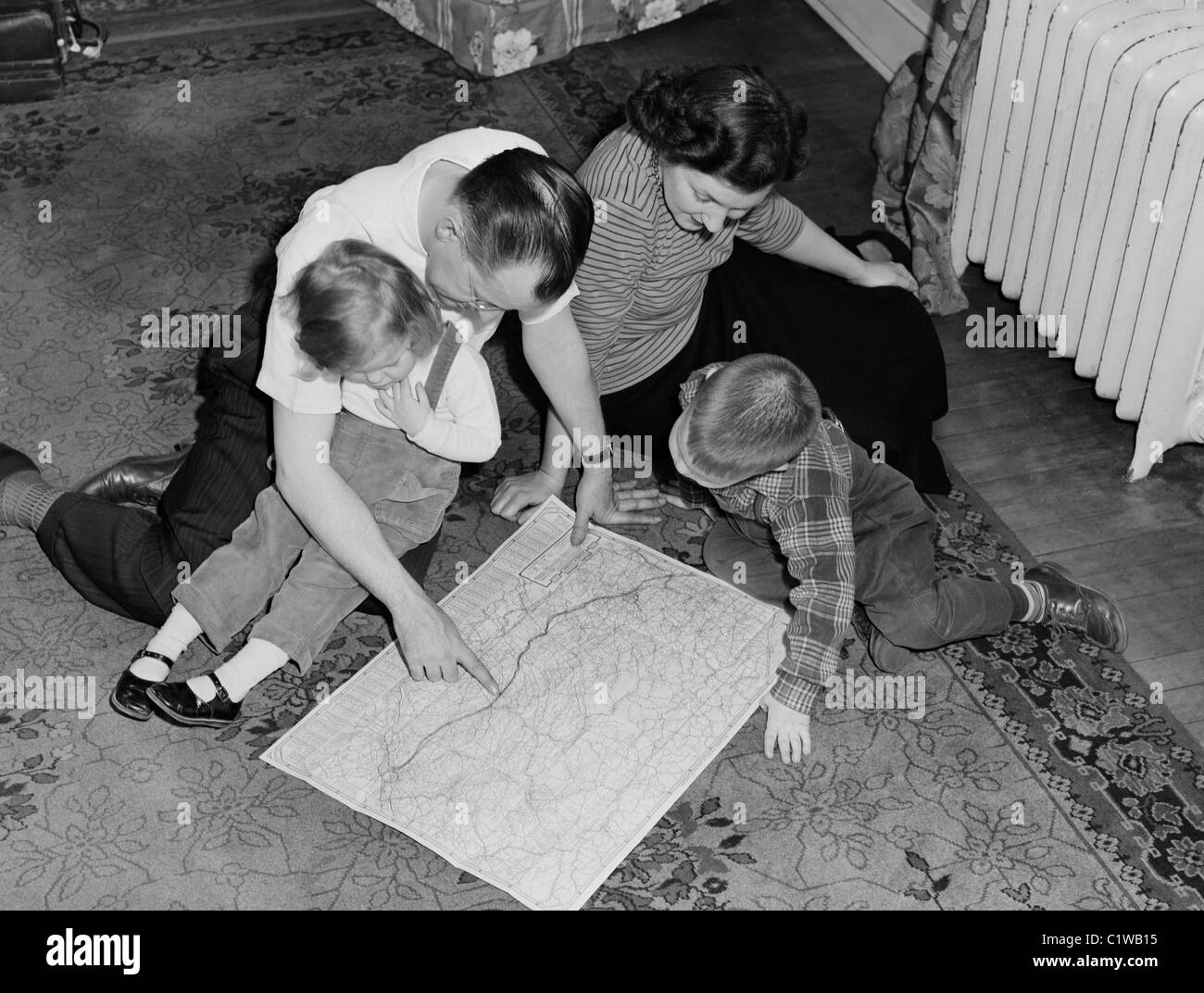 Les parents avec des enfants assis sur le plancher à la recherche à la carte Banque D'Images