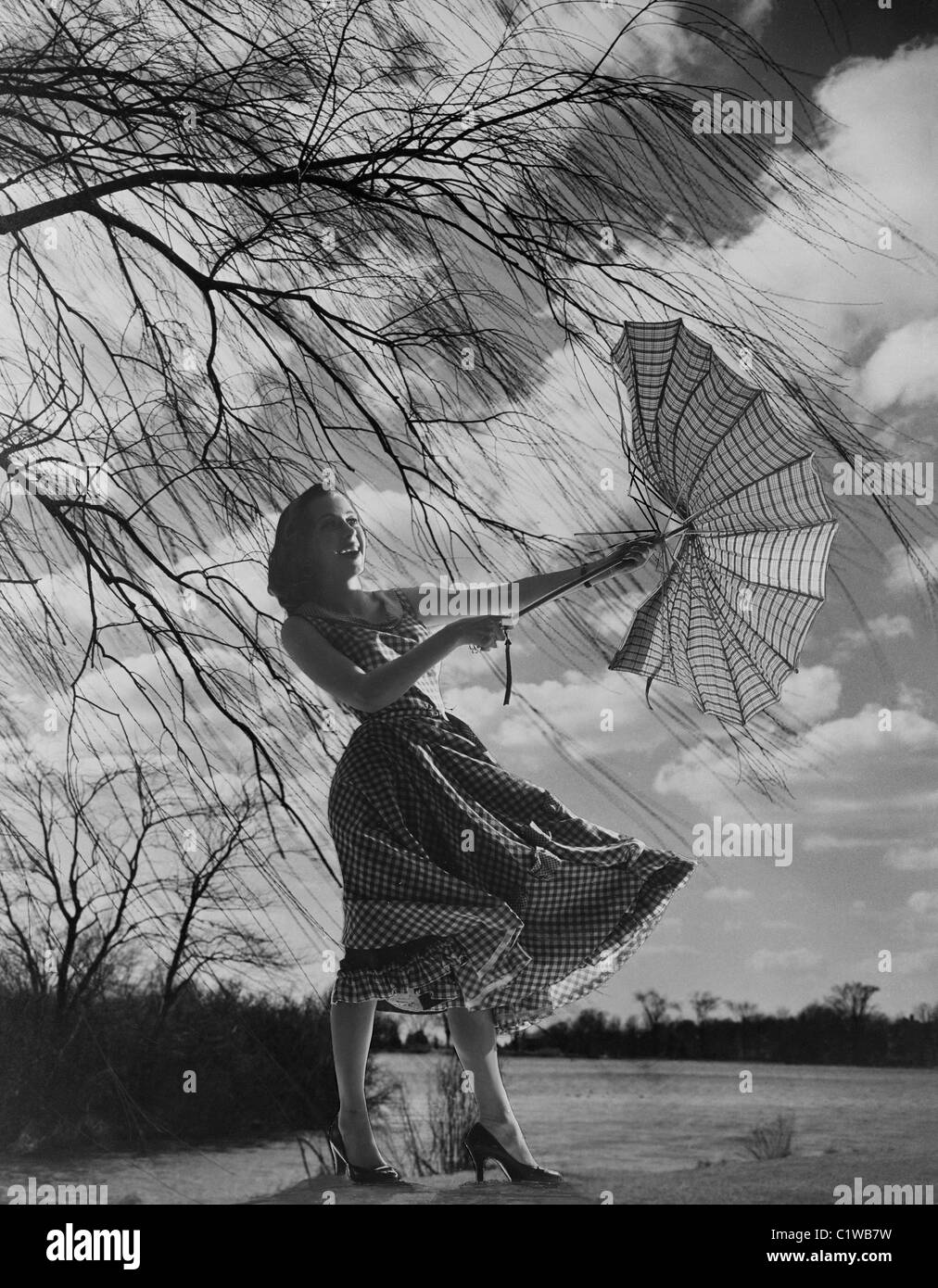 Woman holding umbrella dans le vent fort Banque D'Images