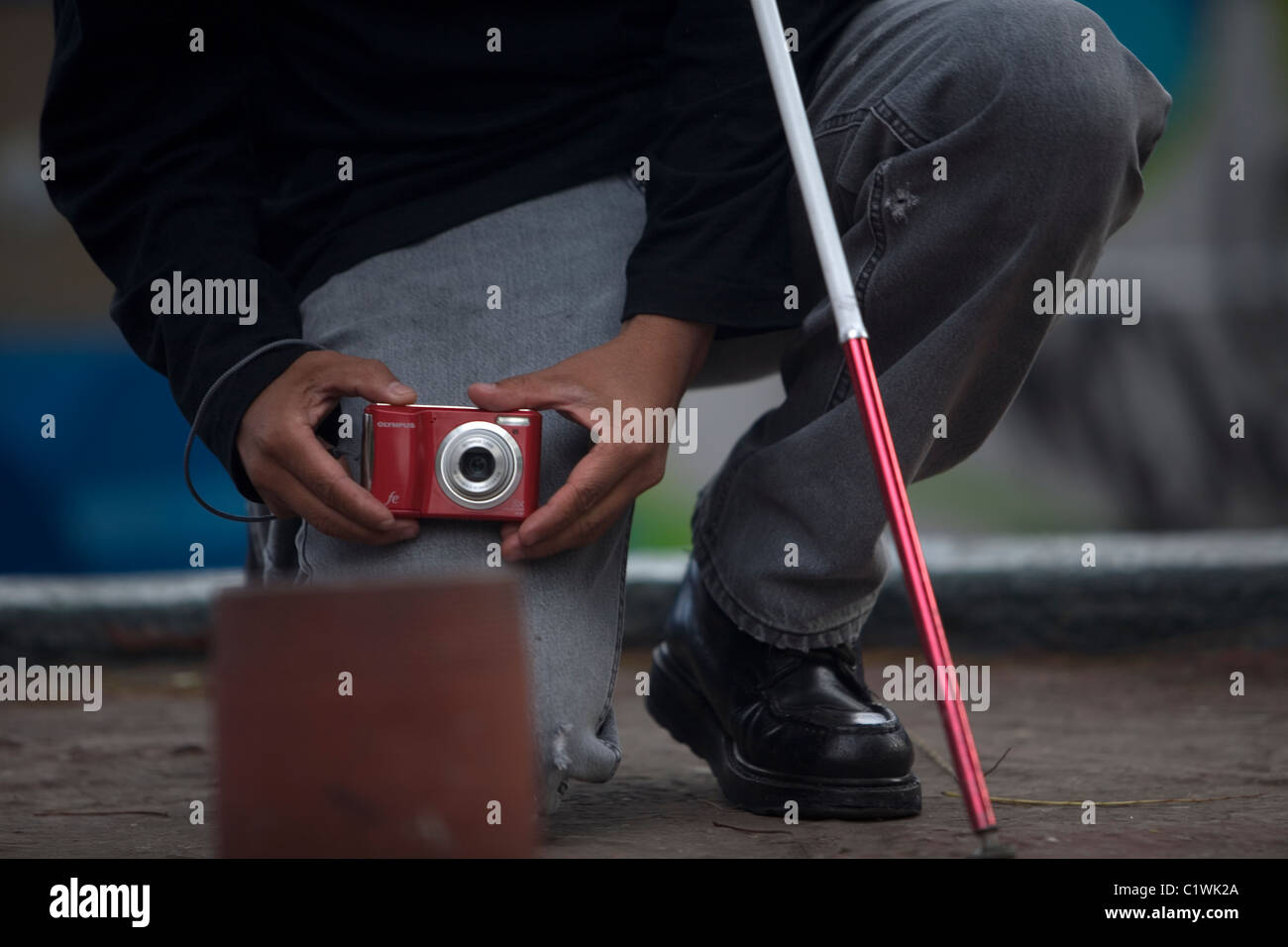 Un photographe aveugle prend des photos qu'il s'agenouille au cours d'un atelier de photographie pour les aveugles et malvoyants, Mexico City Banque D'Images