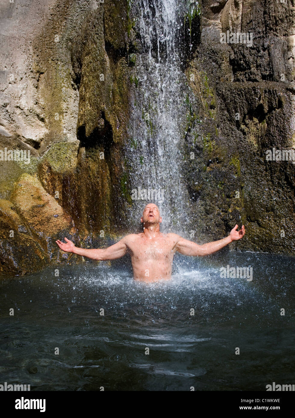 Un homme jouissant d'une cascade naturelle et la piscine. Banque D'Images