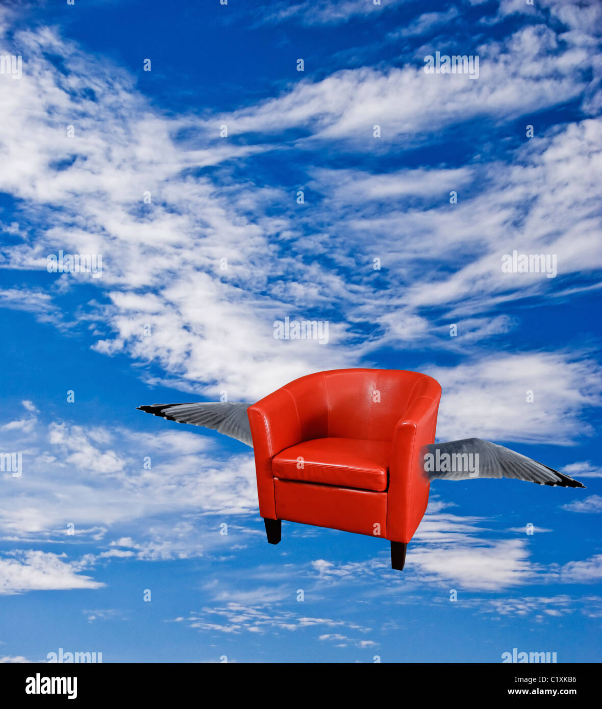 Fauteuil en cuir rouge, volant avec des ailes qui volent dans le ciel. Banque D'Images