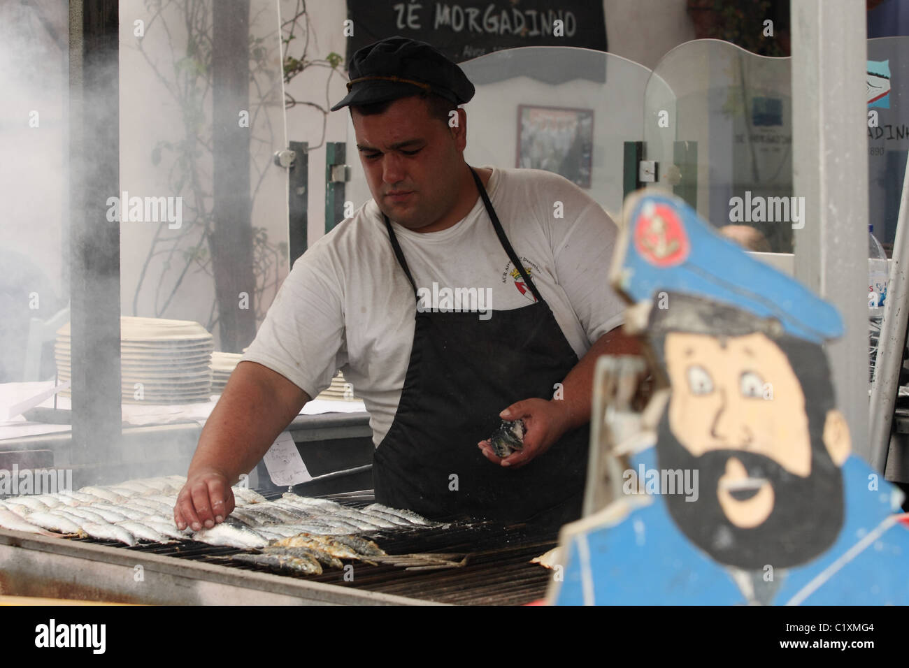 Un portugais grillades de sardines sur un feu de charbon à l'extérieur d'un restaurant sur la rue à Alvor. Algarve Portugal Banque D'Images