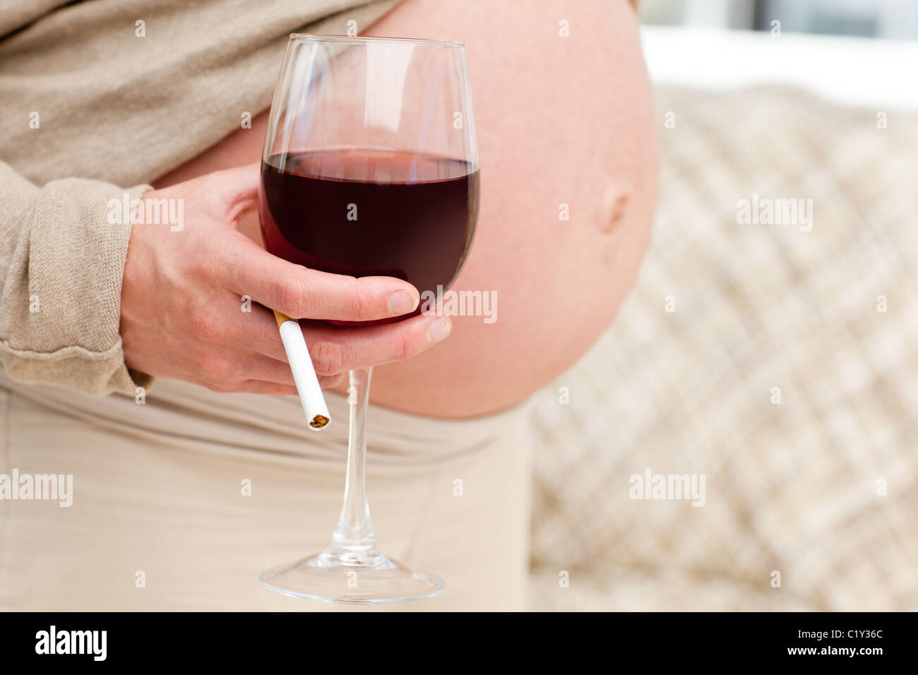 Futur maman avec un verre de vin et de cigarettes Banque D'Images