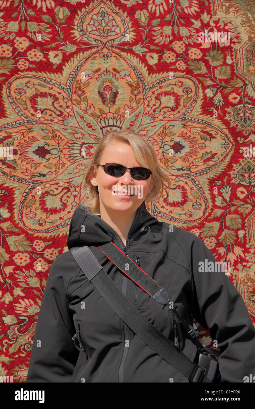 Touristiques blonde girl with sunglasses devant un tapis traditionnels turcs formant un halo Banque D'Images
