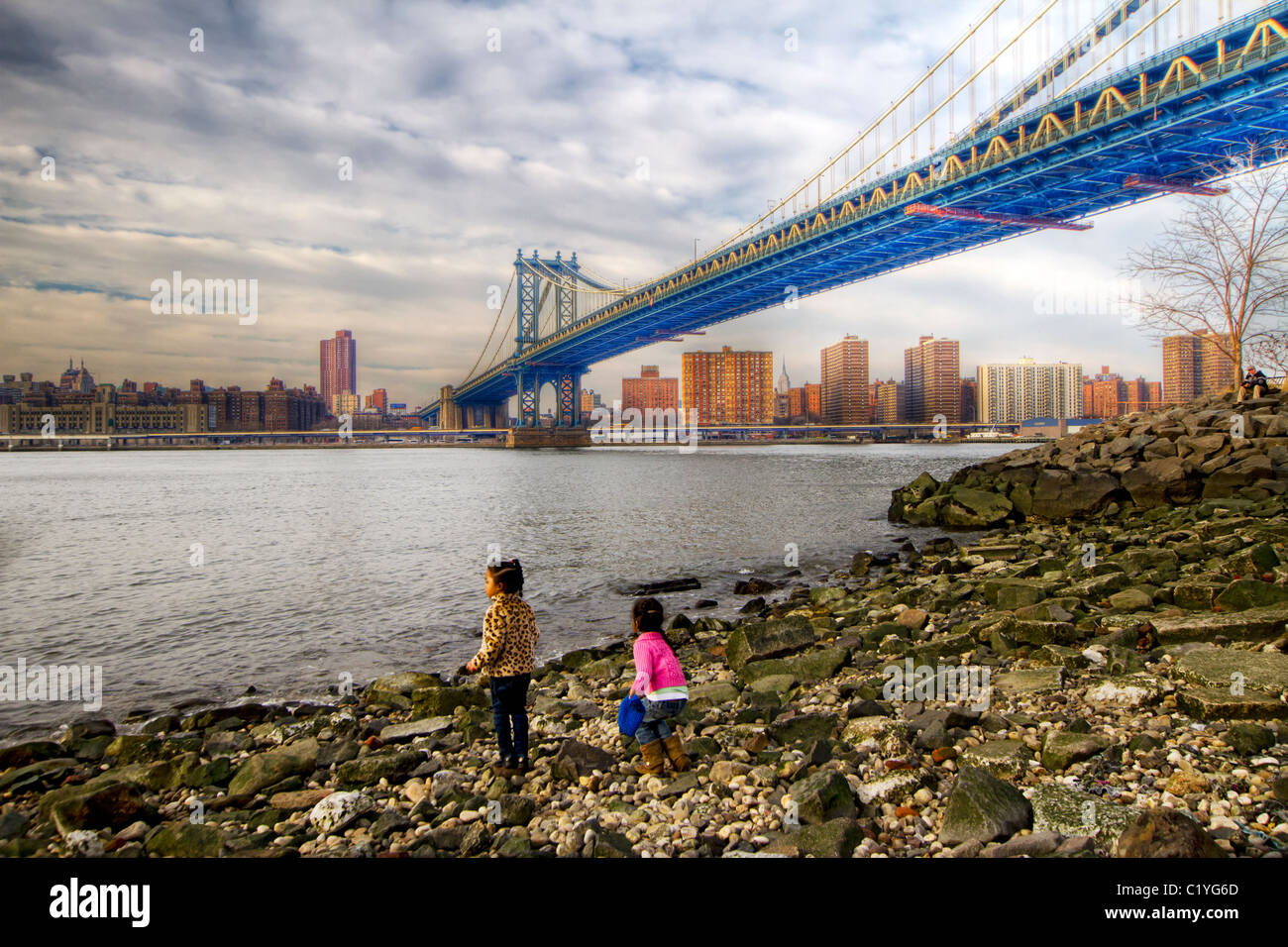 Enfants jouant près du bord de l'East River avec le Pont de Manhattan en arrière-plan à Brooklyn Bridge Park à Brooklyn Banque D'Images