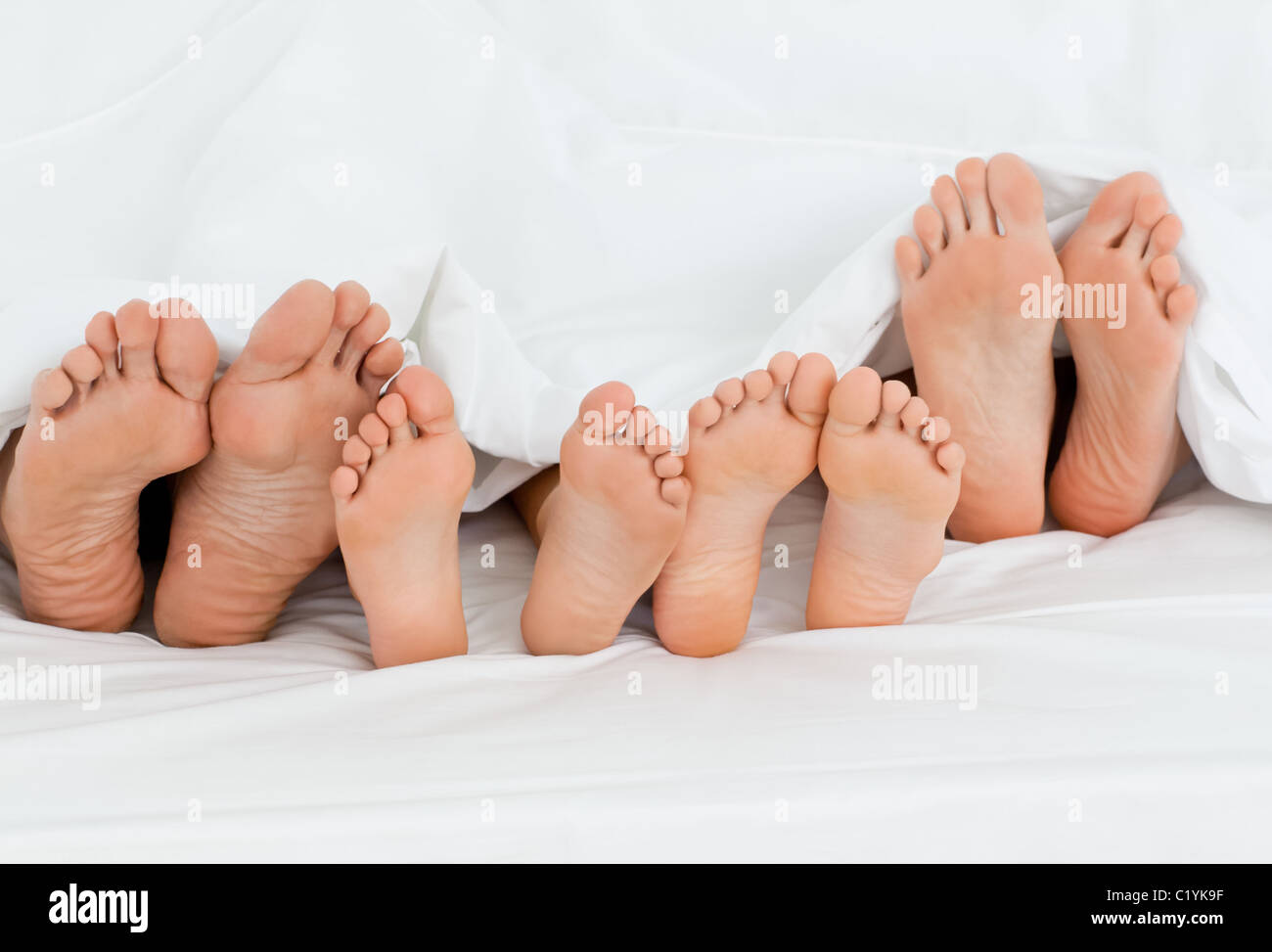 Sur le lit de la famille à la maison avec leurs pieds montrant Banque D'Images