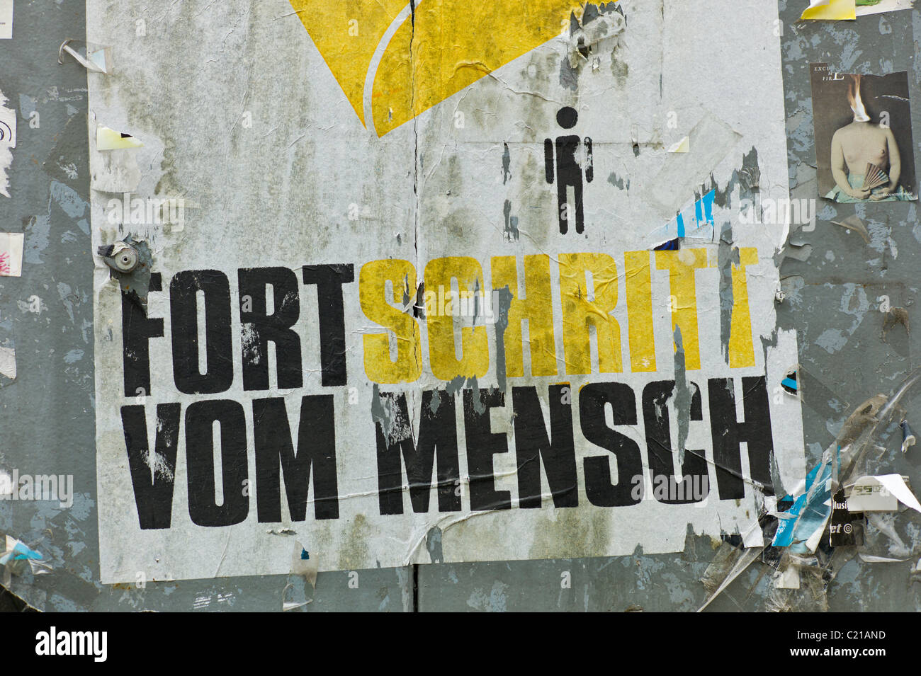 L'art de l'affiche sur "FORTSCHRITT VOM MENSCH' montrant une personne minuscule situé sous un abrégé pied jaune, Gärternplatzviertel, Munich Banque D'Images