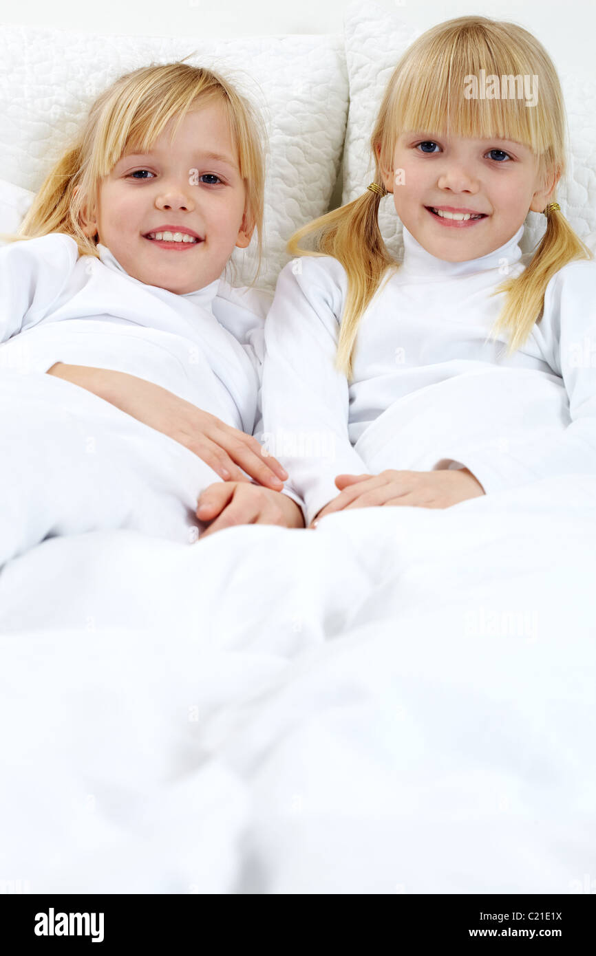Portrait de deux adorables sœurs couché dans le lit Banque D'Images