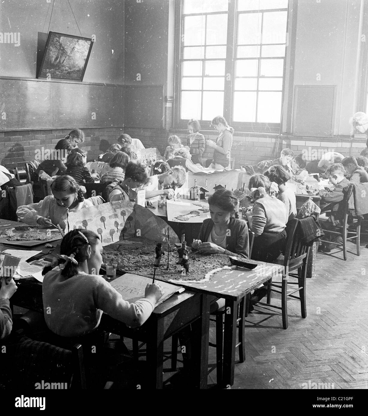 1950s, enfants historiques de l'école primaire assis à des bureaux dans la salle de classe faisant des activités; dessin, peinture et faire des maquettes en papier, Angleterre, Royaume-Uni. Banque D'Images