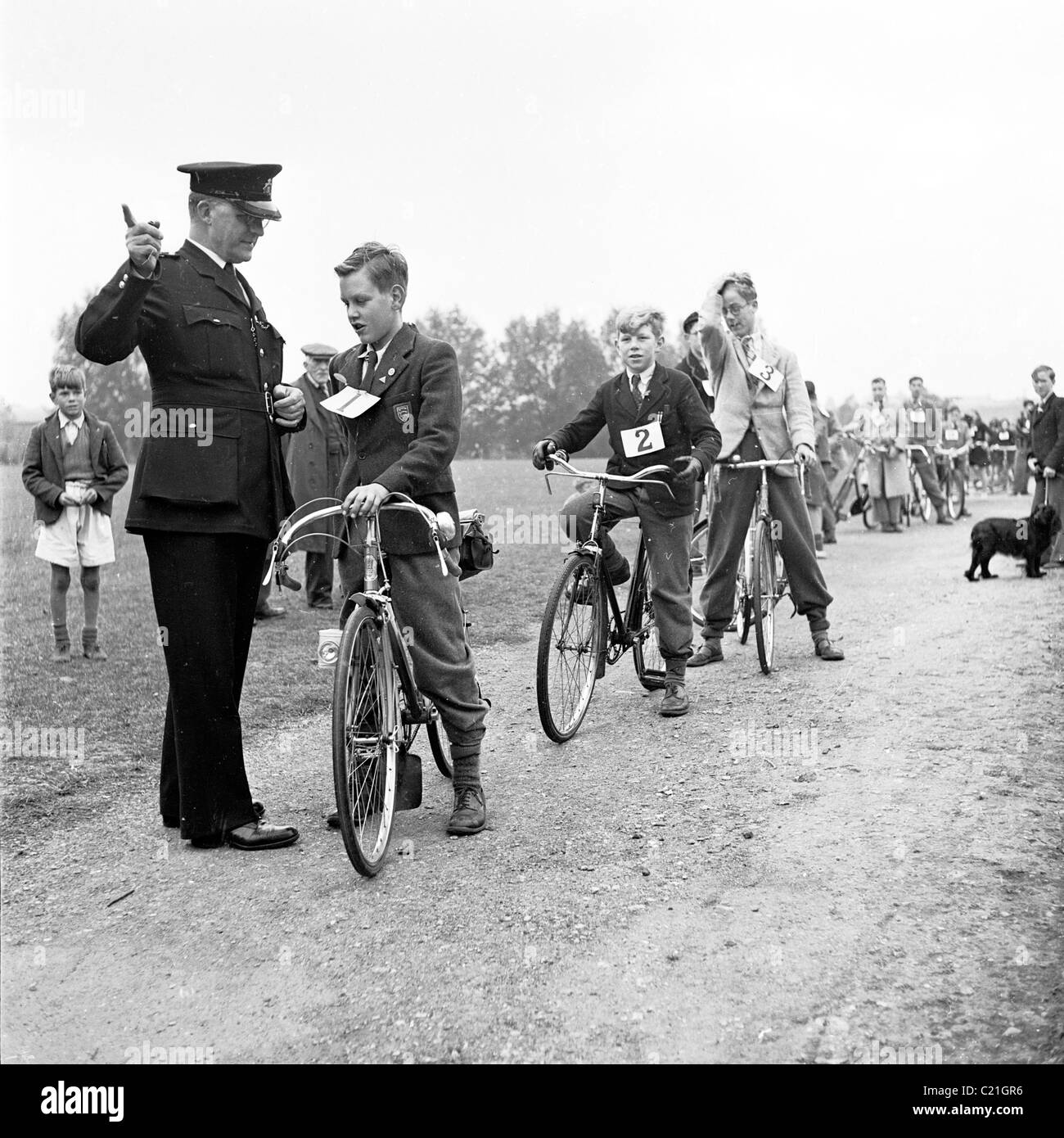 1950s, historique, à l'extérieur sur un chemin, un policier lance de jeunes écoliers à leur test de maîtrise du cyclisme, Londres, Angleterre, Royaume-Uni. Banque D'Images