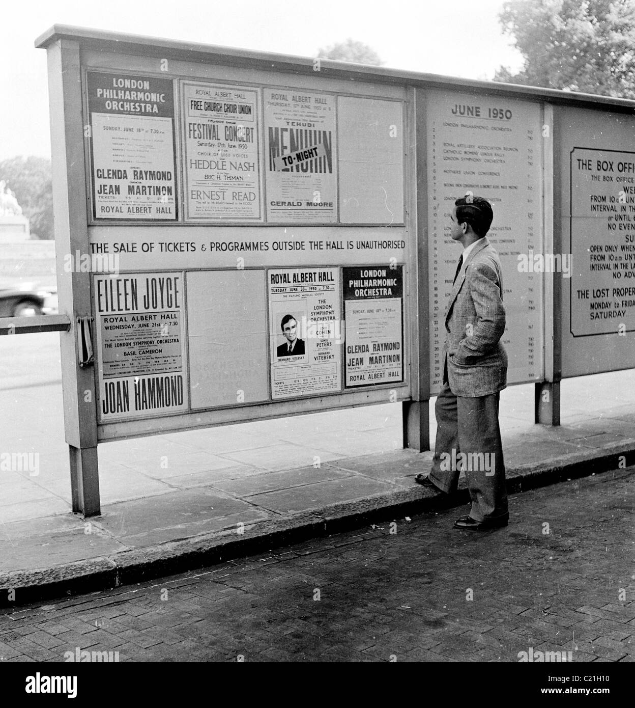 Le 1950 juin, Londres, un homme nouvellement arrivé immigrant en Grande-Bretagne étudie un comité d'affichage énumérant des événements au Royal Albert Hall, Yehudi Menuhin apparaissant. Banque D'Images