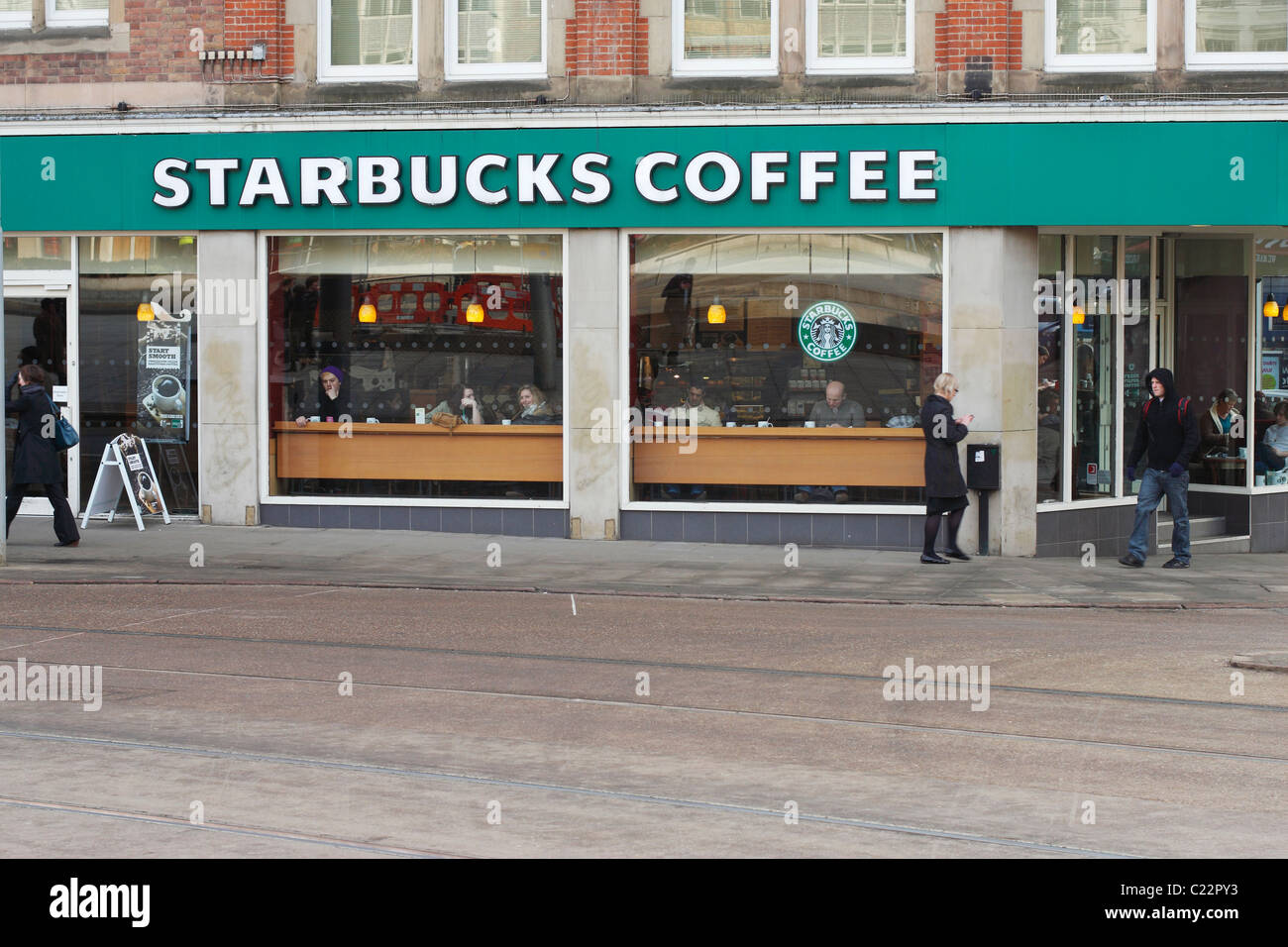 Un café Starbucks dans le centre-ville de Nottingham, au Royaume-Uni. Les gens assis à parler, lire et boire du café dans la fenêtre. Banque D'Images