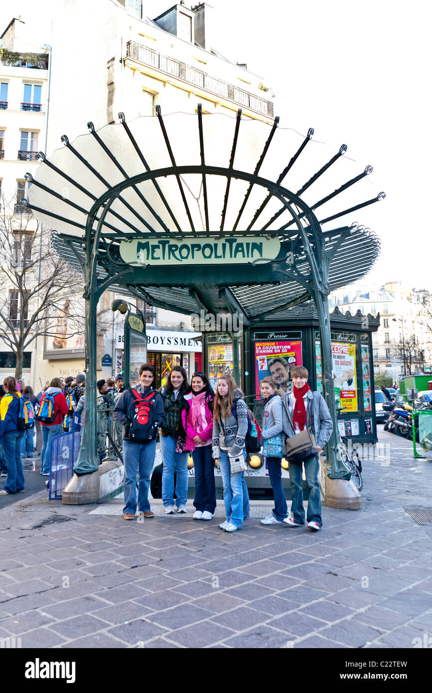 Un voyage organisé pour les jeunes posent pour une photo devant un métro Metropolitain art-nouveau panneau ; Paris, France. Charles Lupica Banque D'Images