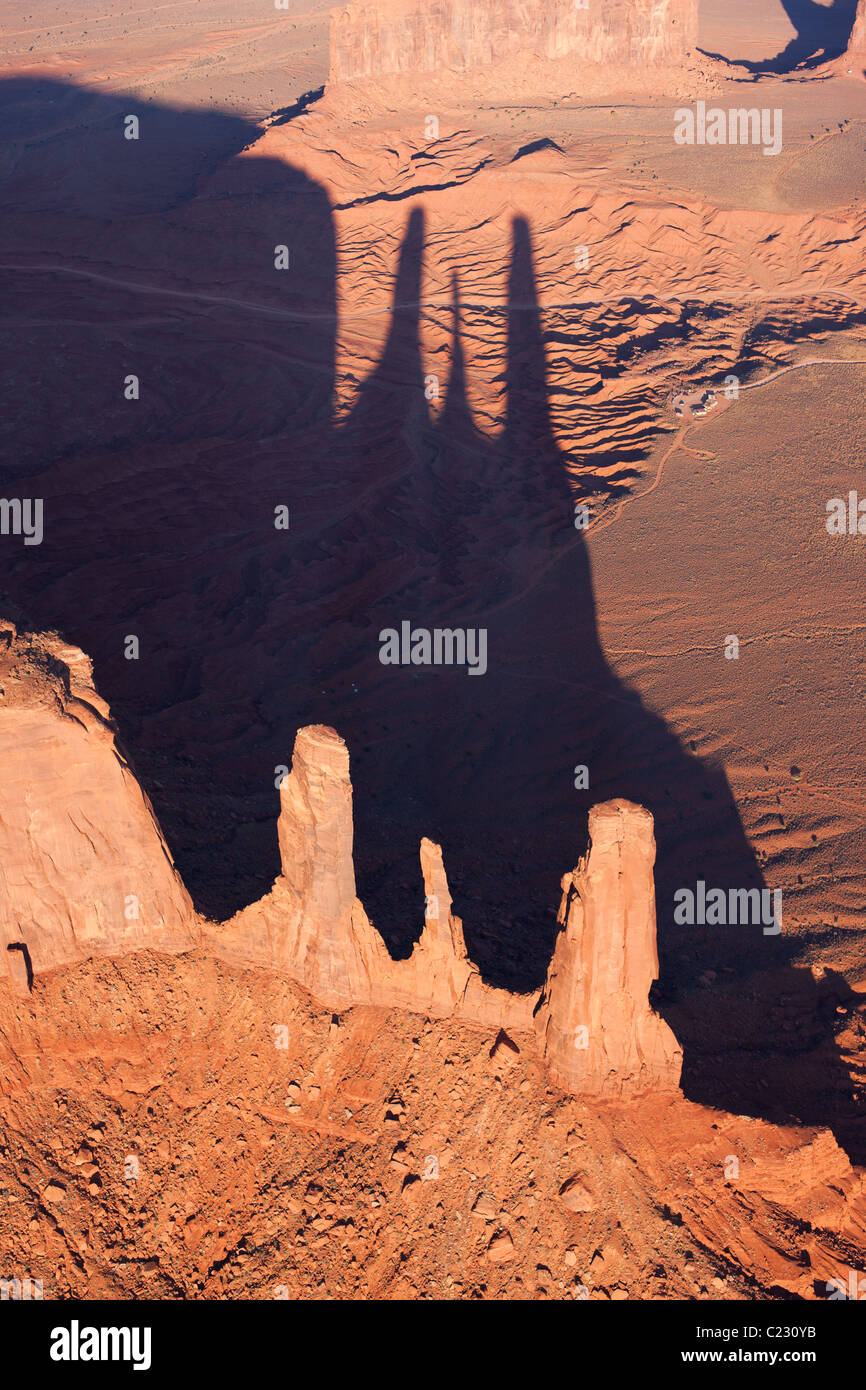 VUE AÉRIENNE.Trois sœurs en formation rocheuse jettent leurs longues ombres sur le sol du désert.Terre indienne Navajo, comté de Navajo, Arizona, États-Unis. Banque D'Images