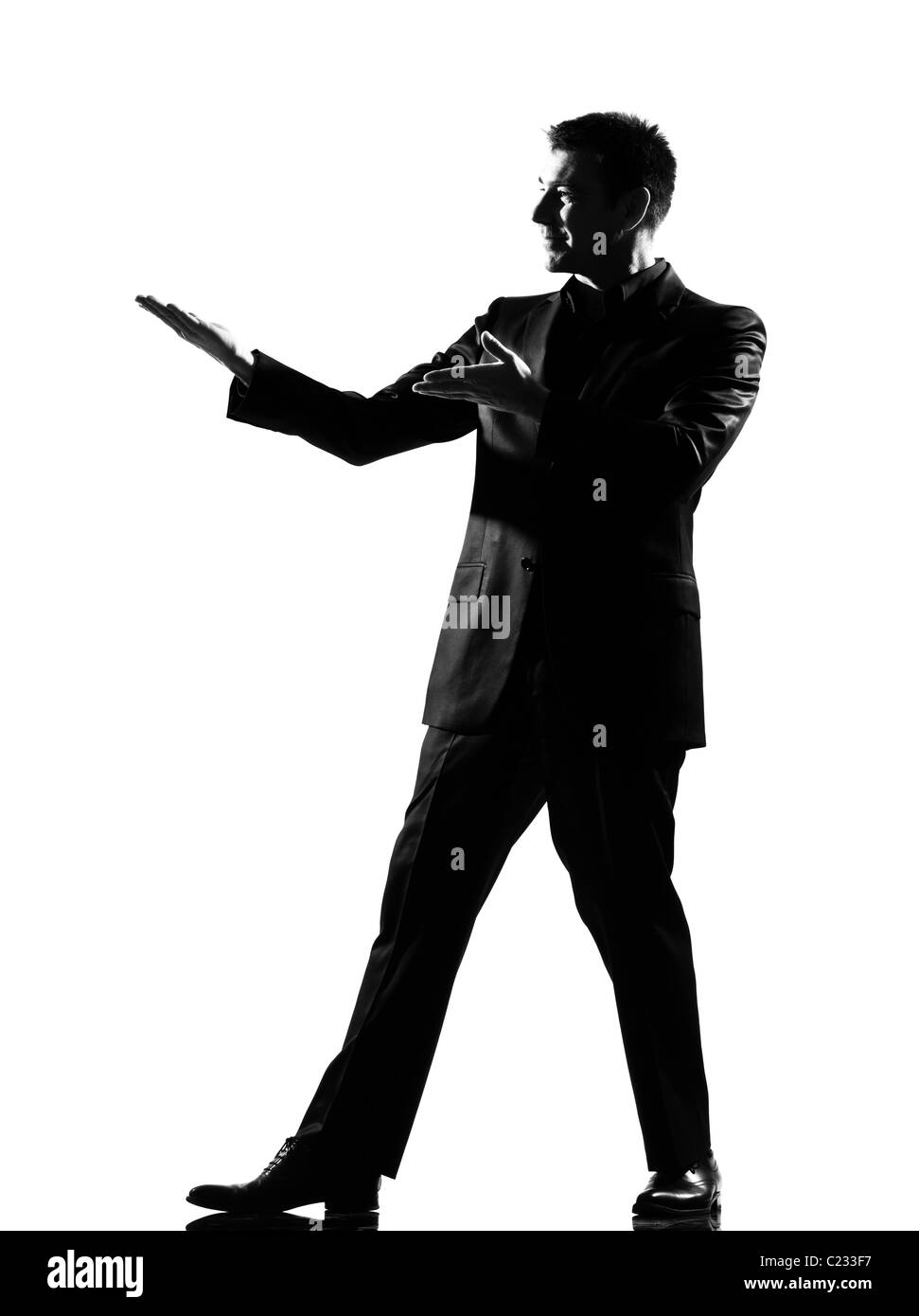 Silhouette caucasian business homme presentationsimiling geste exprimant montrant l'introduction de toute la longueur du comportement sur studio Banque D'Images